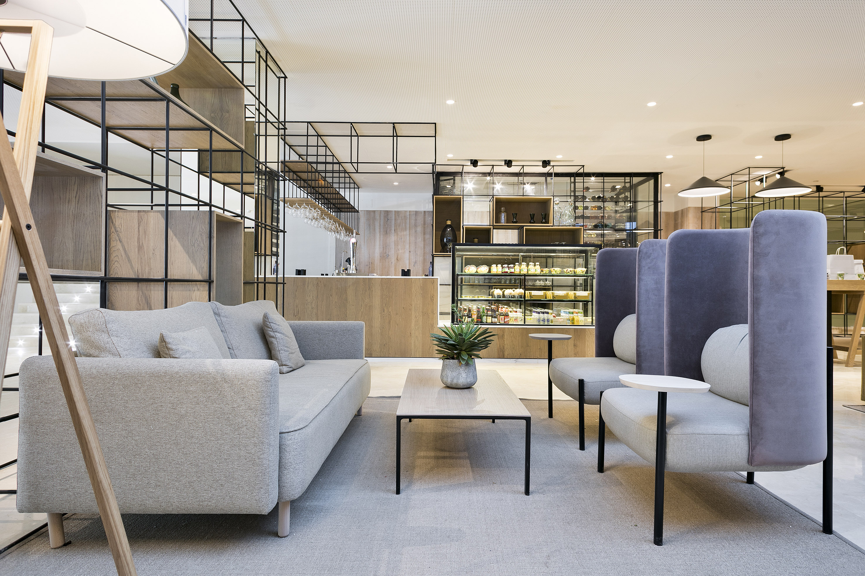 Contemporary lounge with sofa, high-back chairs, bar, and café display.
