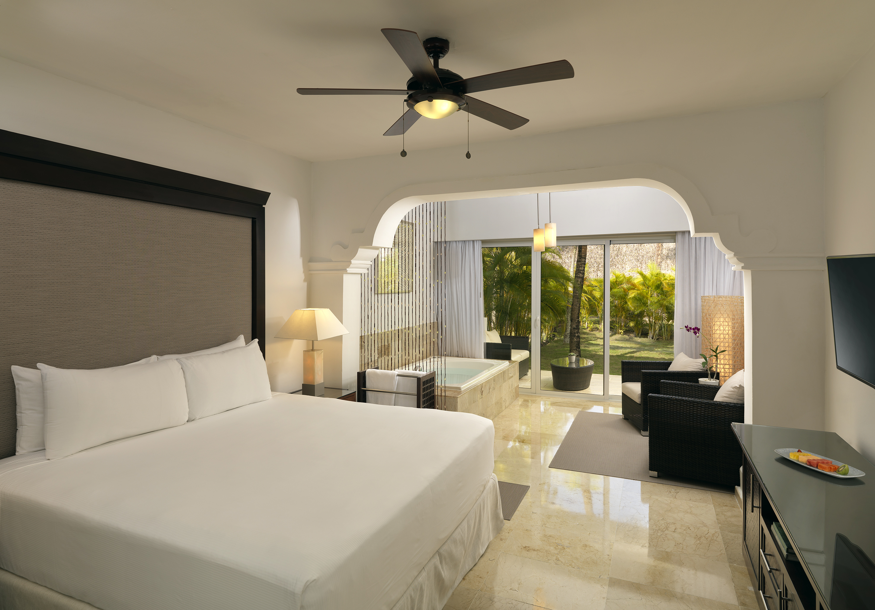 Elegant hotel suite with king bed, private jacuzzi, and lush garden patio.