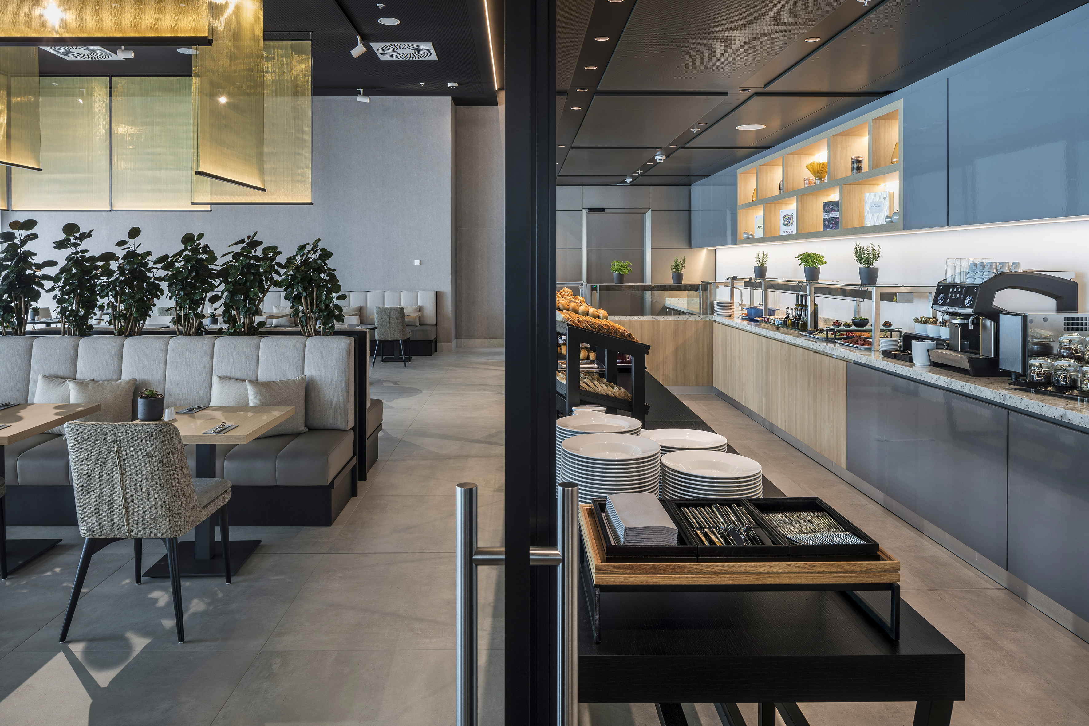 Modern hotel breakfast buffet and elegant dining area with booth seating.