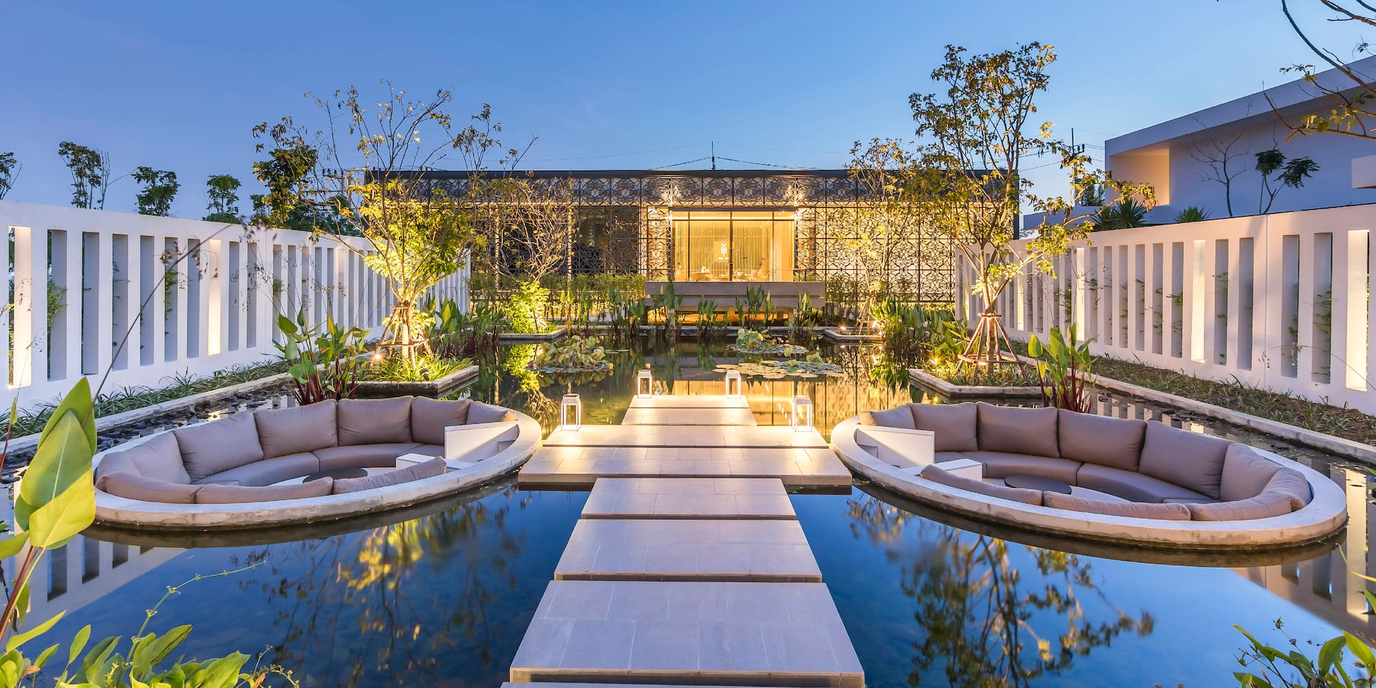 a pool with a walkway and a building with lights