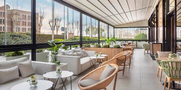 a room with a large glass wall and a white couch and chairs
