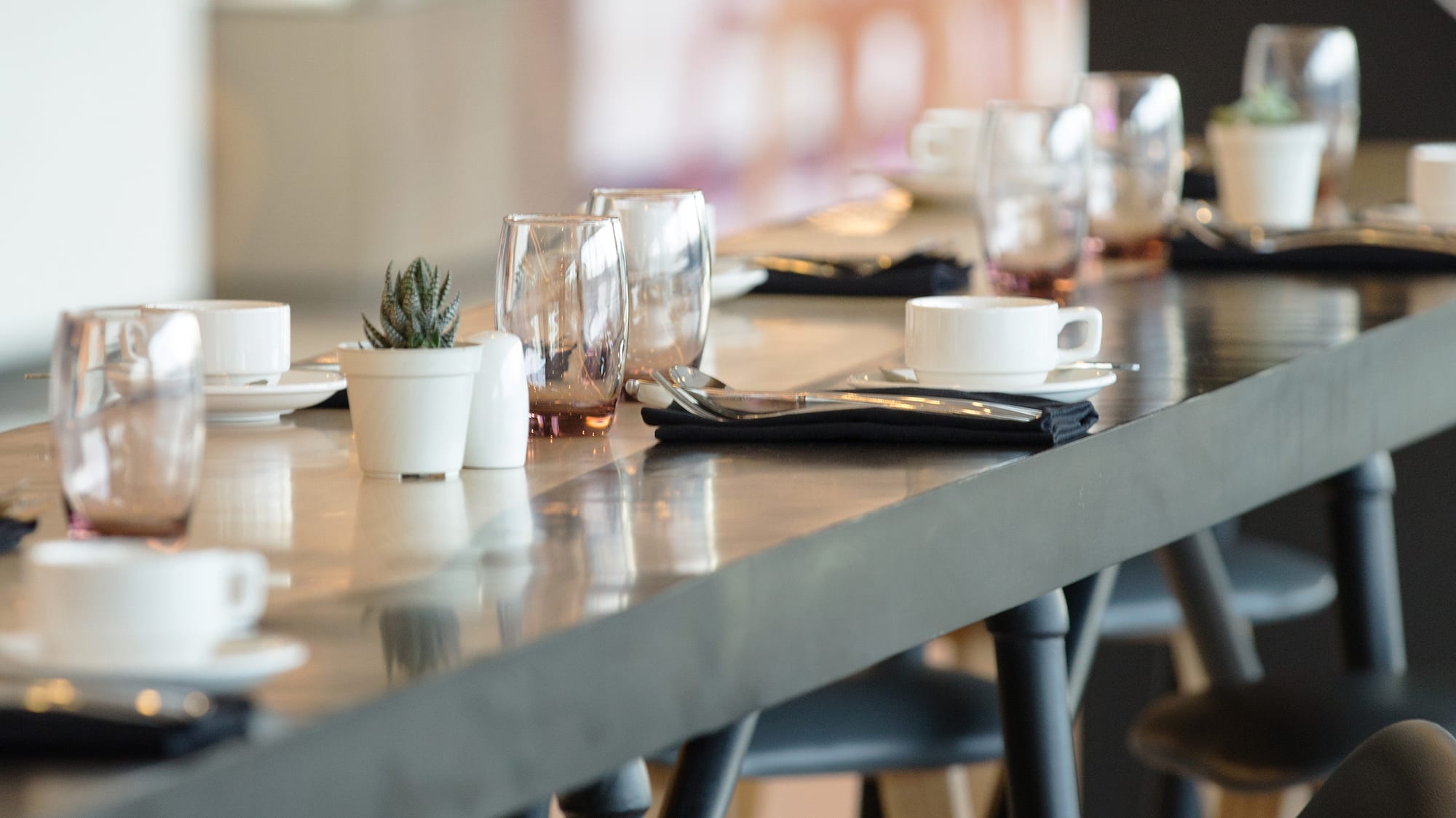 a long table with a row of glasses and napkins