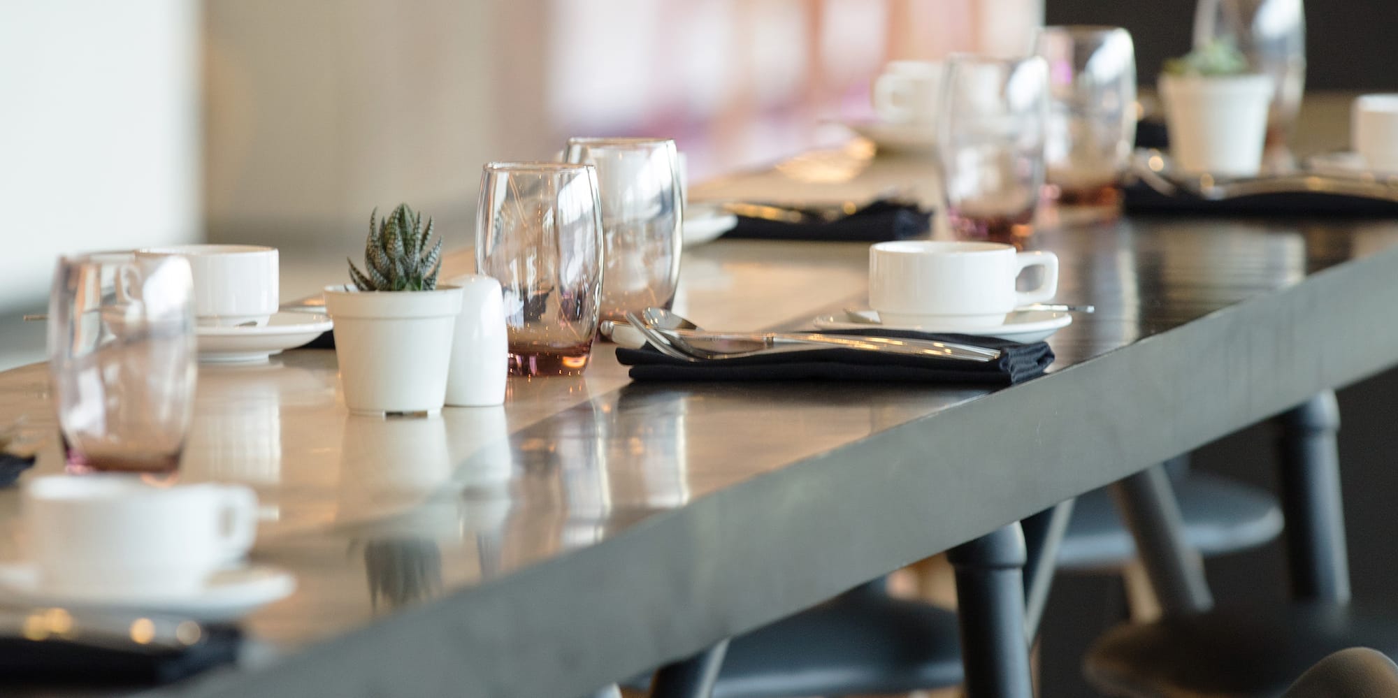 a long table with a row of glasses and napkins