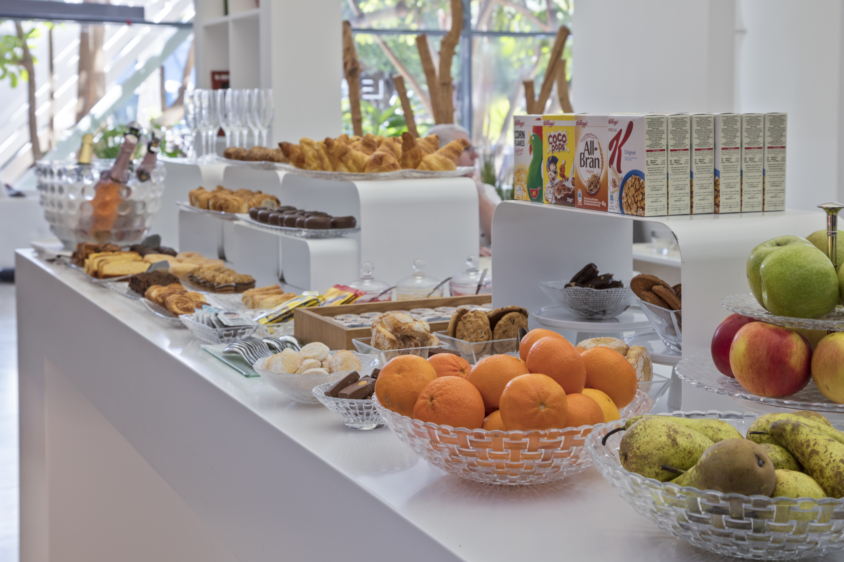Modern breakfast buffet featuring pastries, fresh fruit, Kellogg's cereals, and champagne.