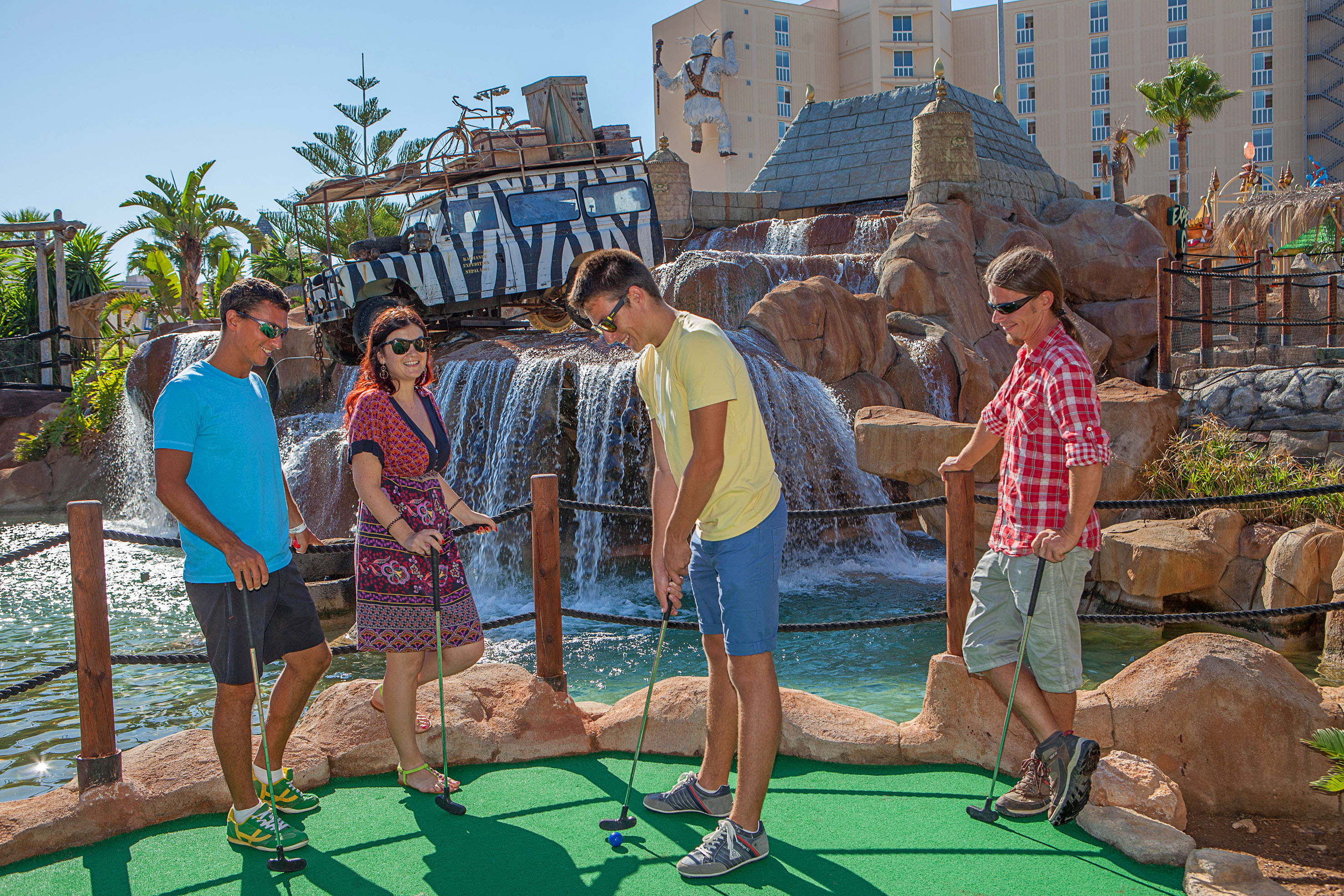 Friends enjoying adventure mini-golf with waterfalls and a safari theme.
