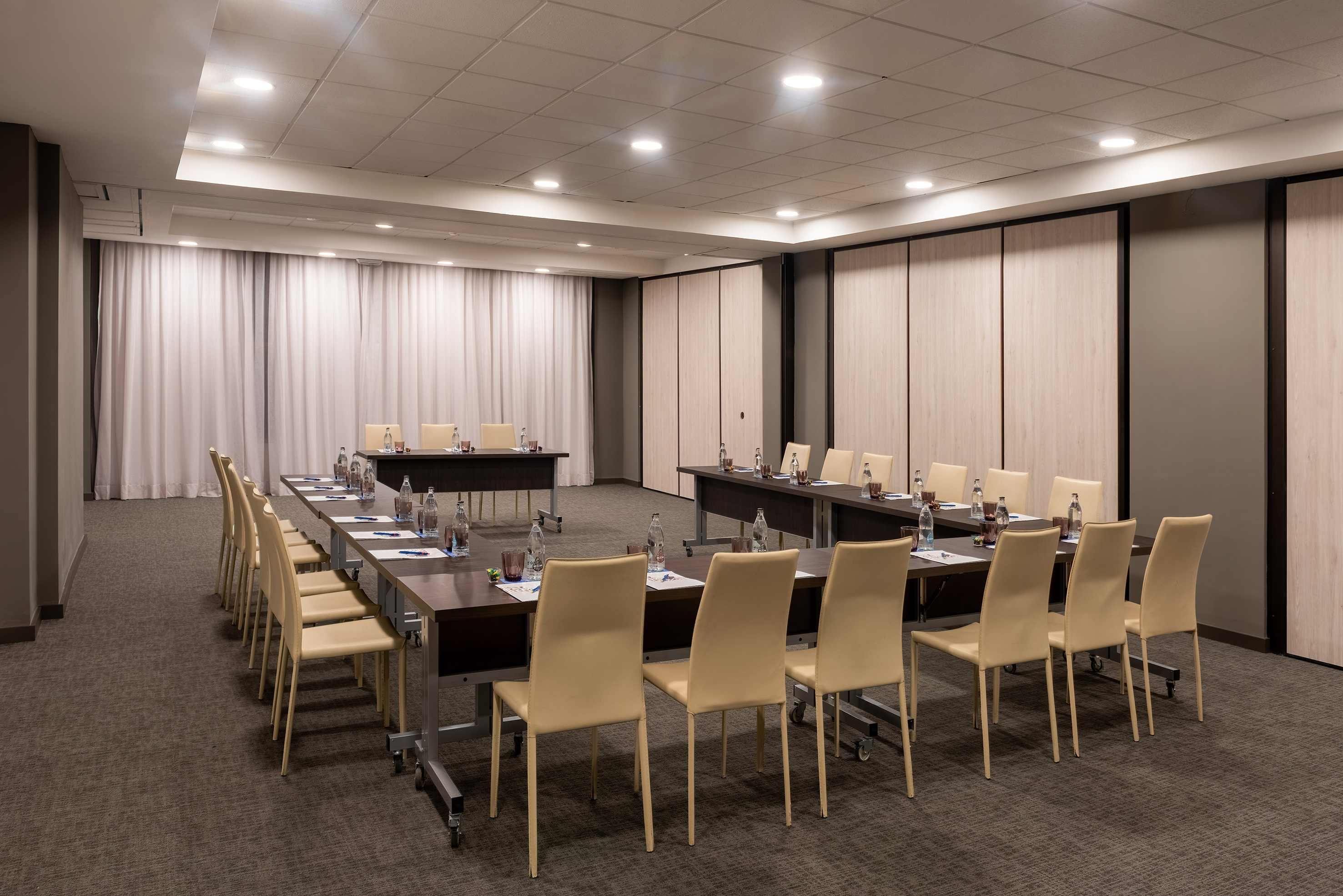 U-shaped conference room setup with dark tables and beige chairs.