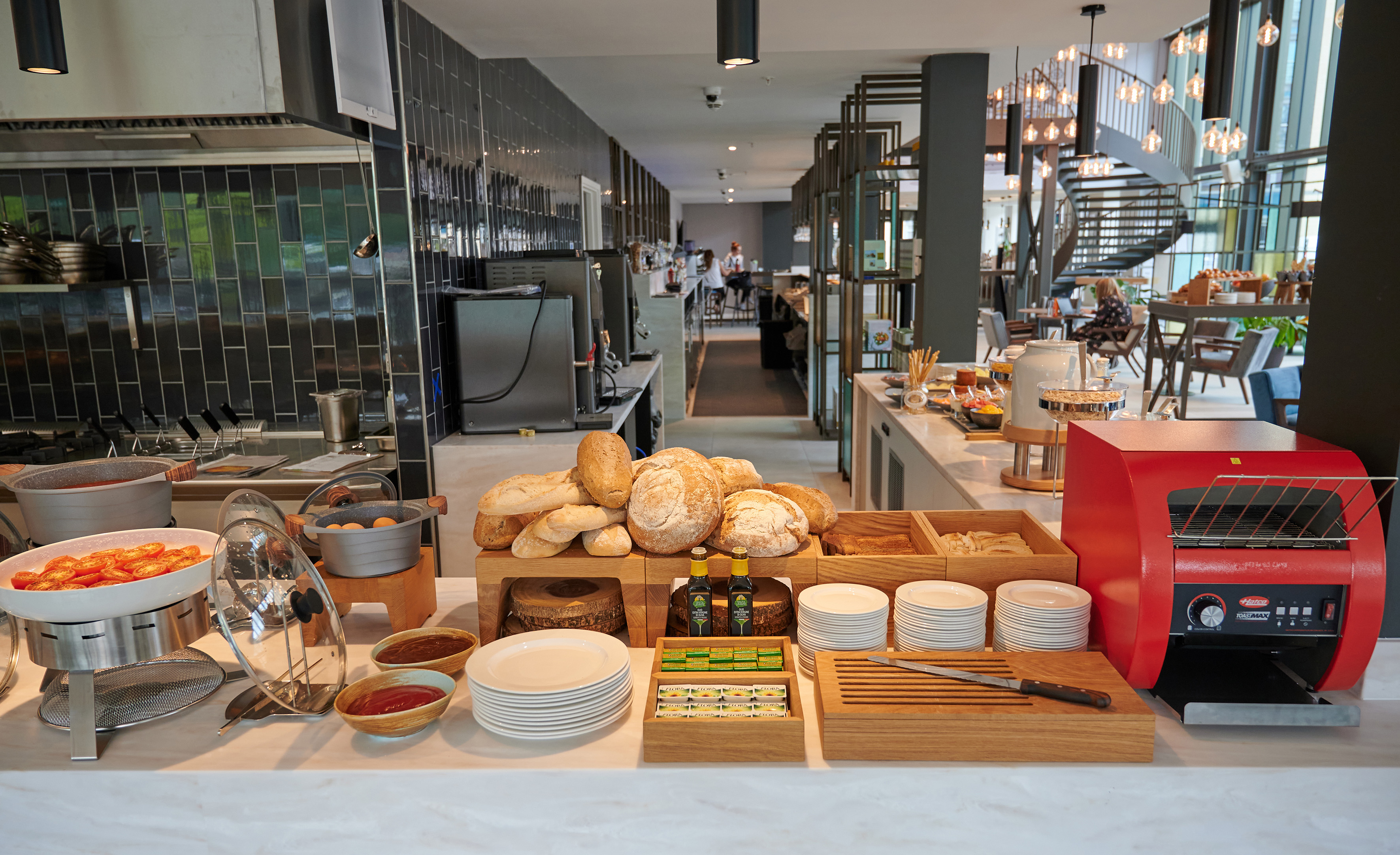 Modern hotel breakfast buffet featuring fresh bread, hot food, and toaster.
