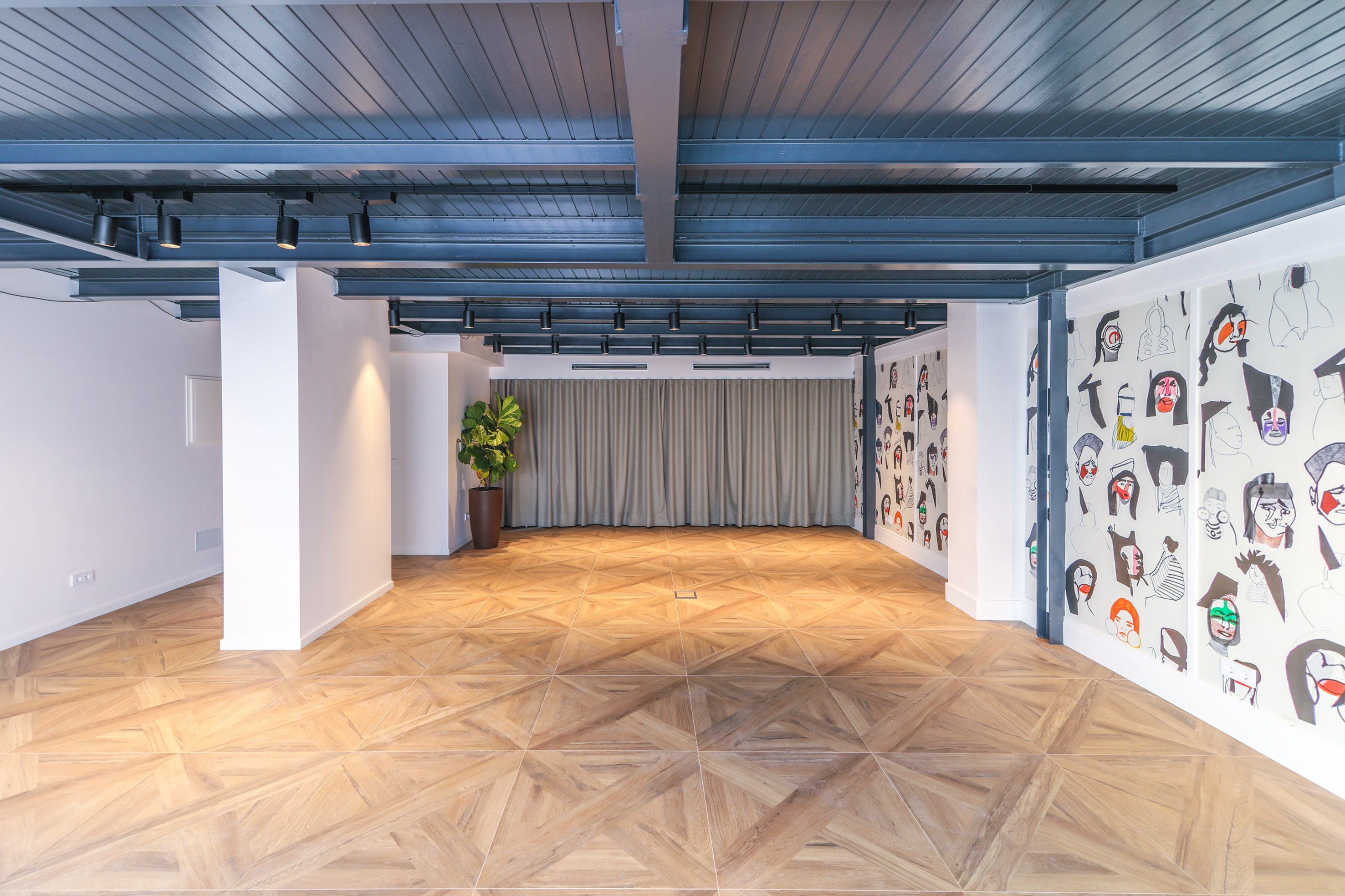 Modern event space with geometric parquet floor, industrial ceiling, and abstract wall art.