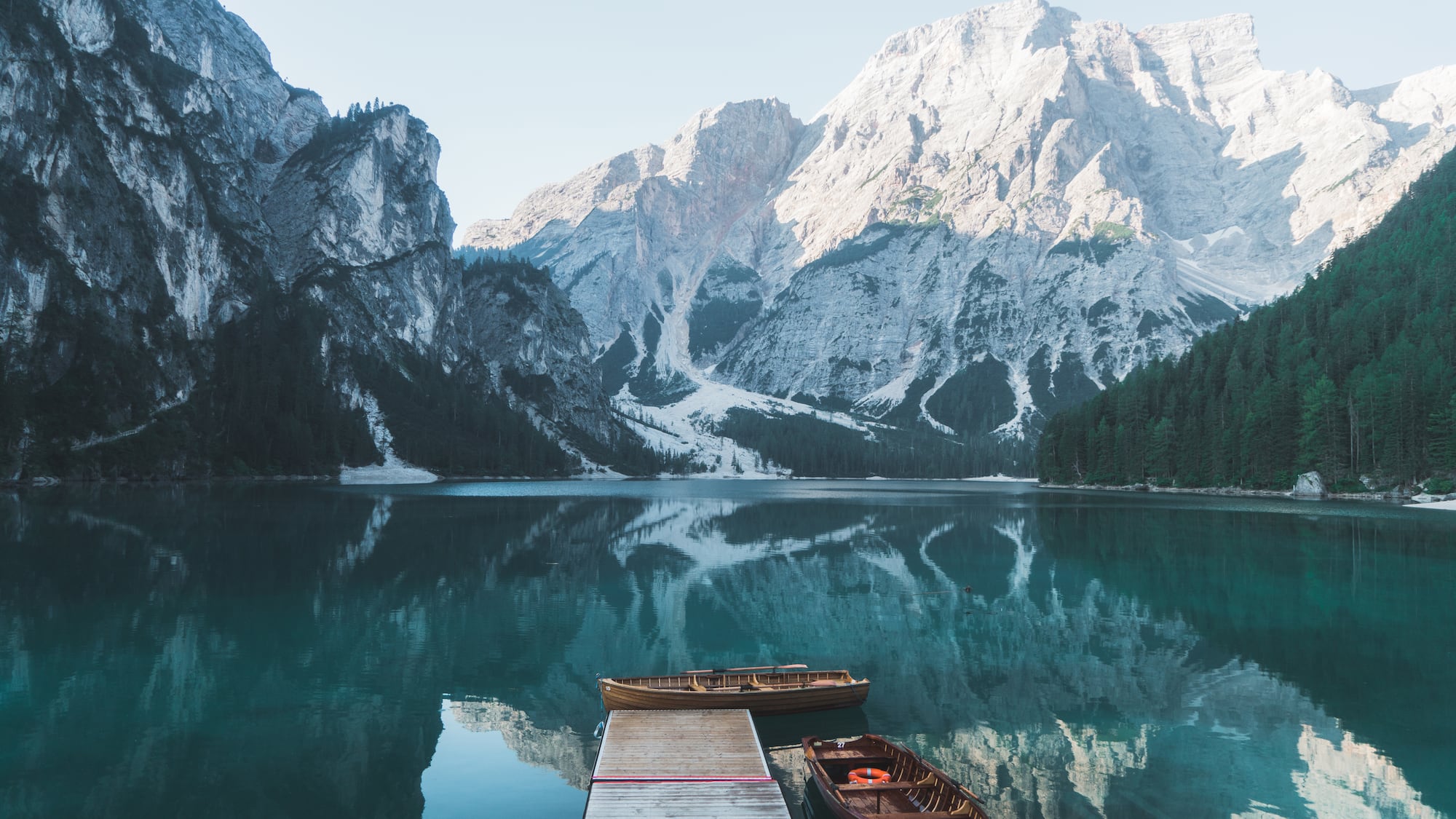 a dock with boats on the water and mountains in the background
