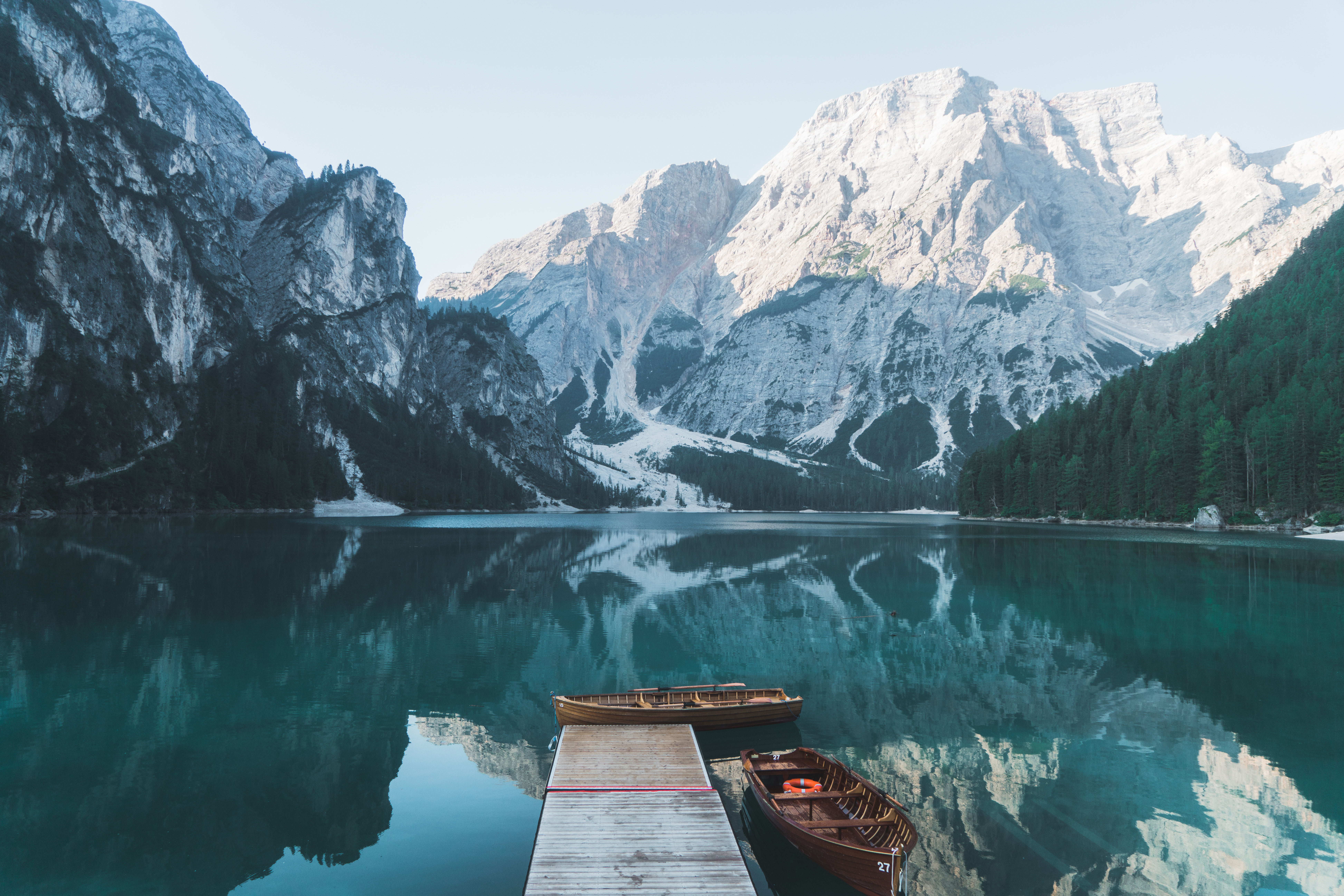 a dock with boats on the water and mountains in the background