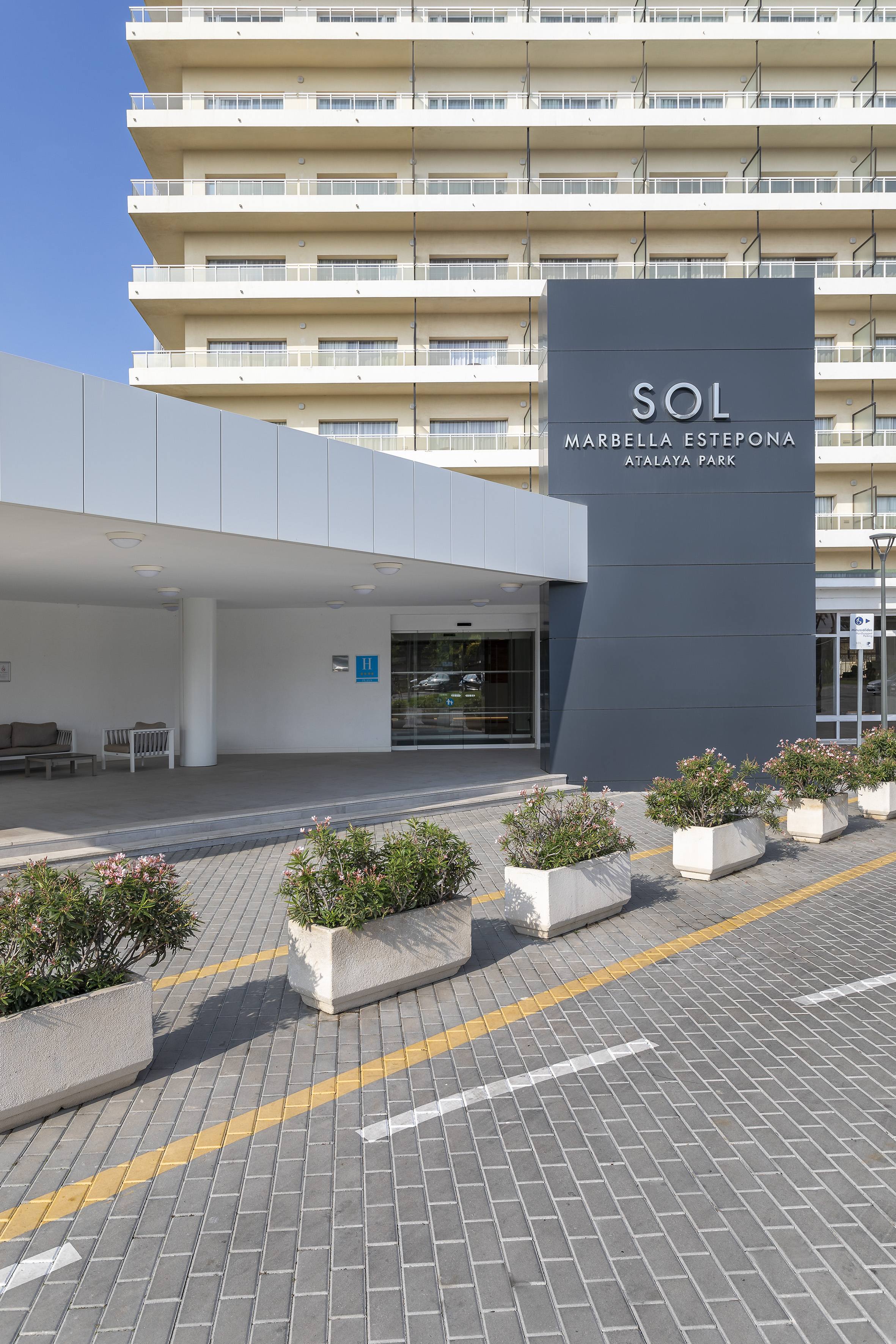 a building with a sign and flowers in front of it