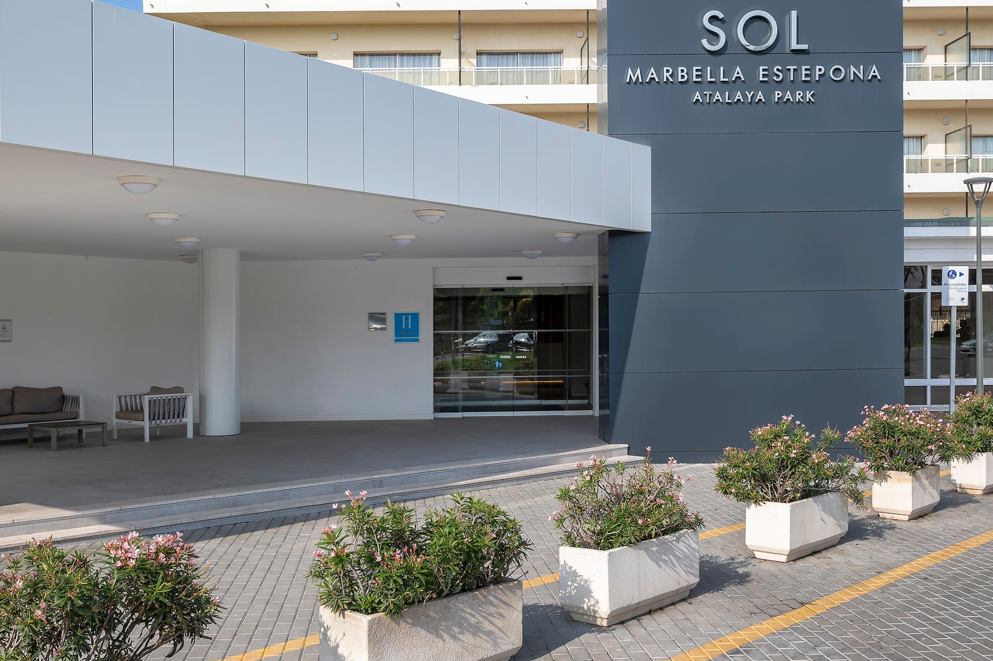 a building with a sign and flowers in front of it