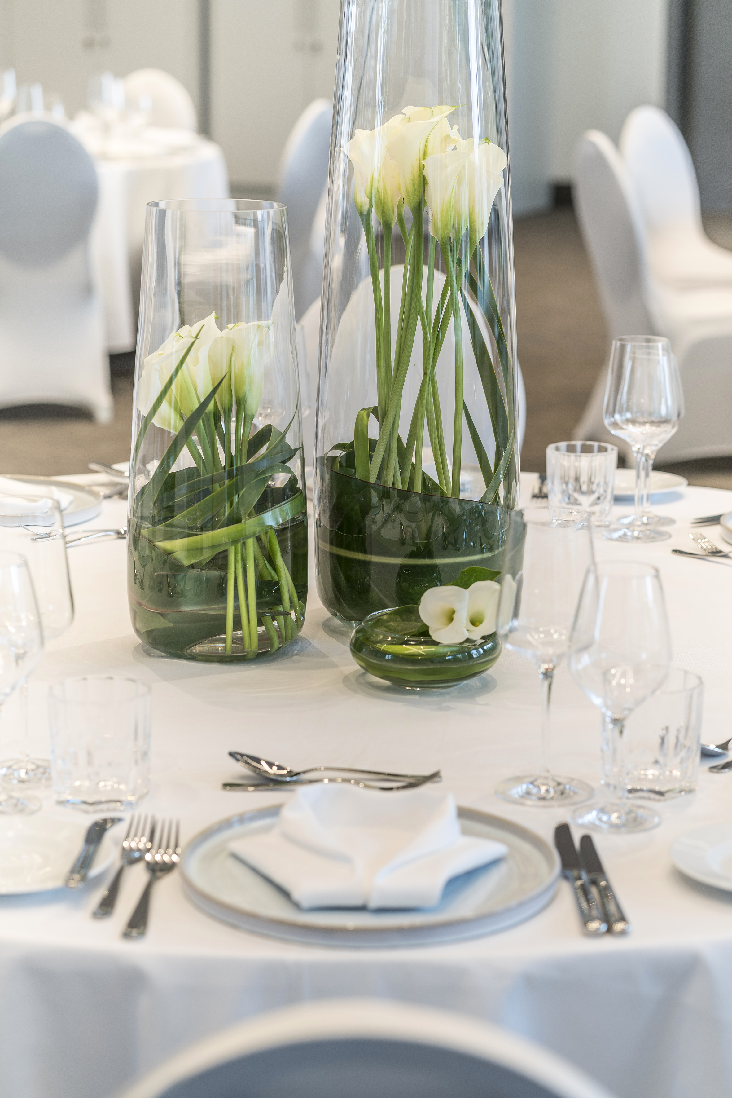 a table set with white and green vases with flowers