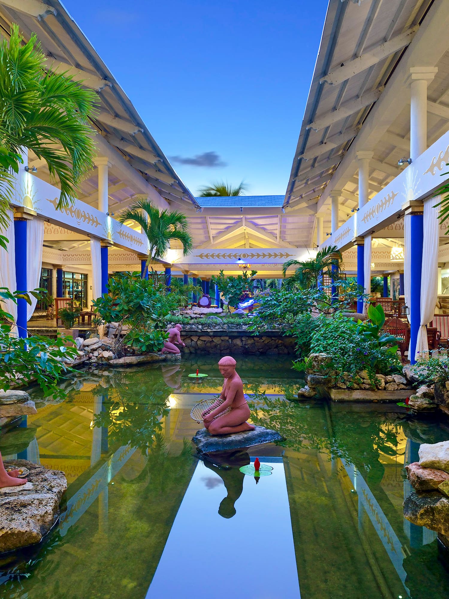 a statue in a pond with trees and plants