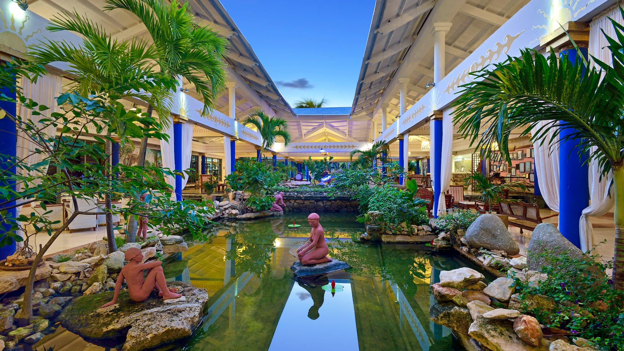 a statue in a pond with trees and plants