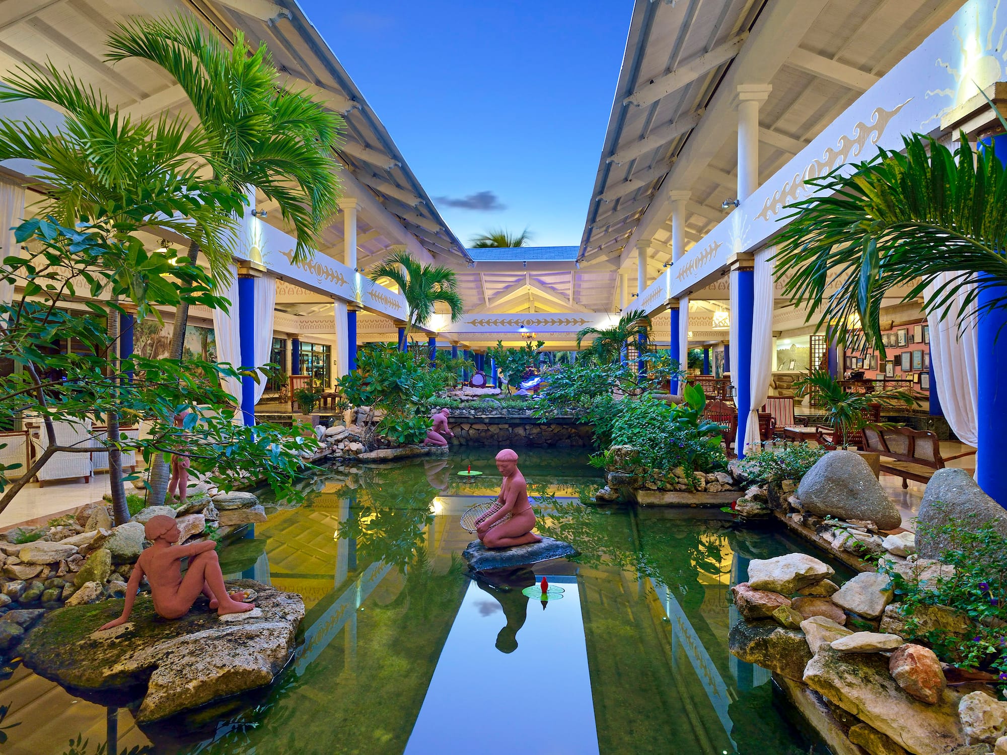 a statue in a pond with trees and plants