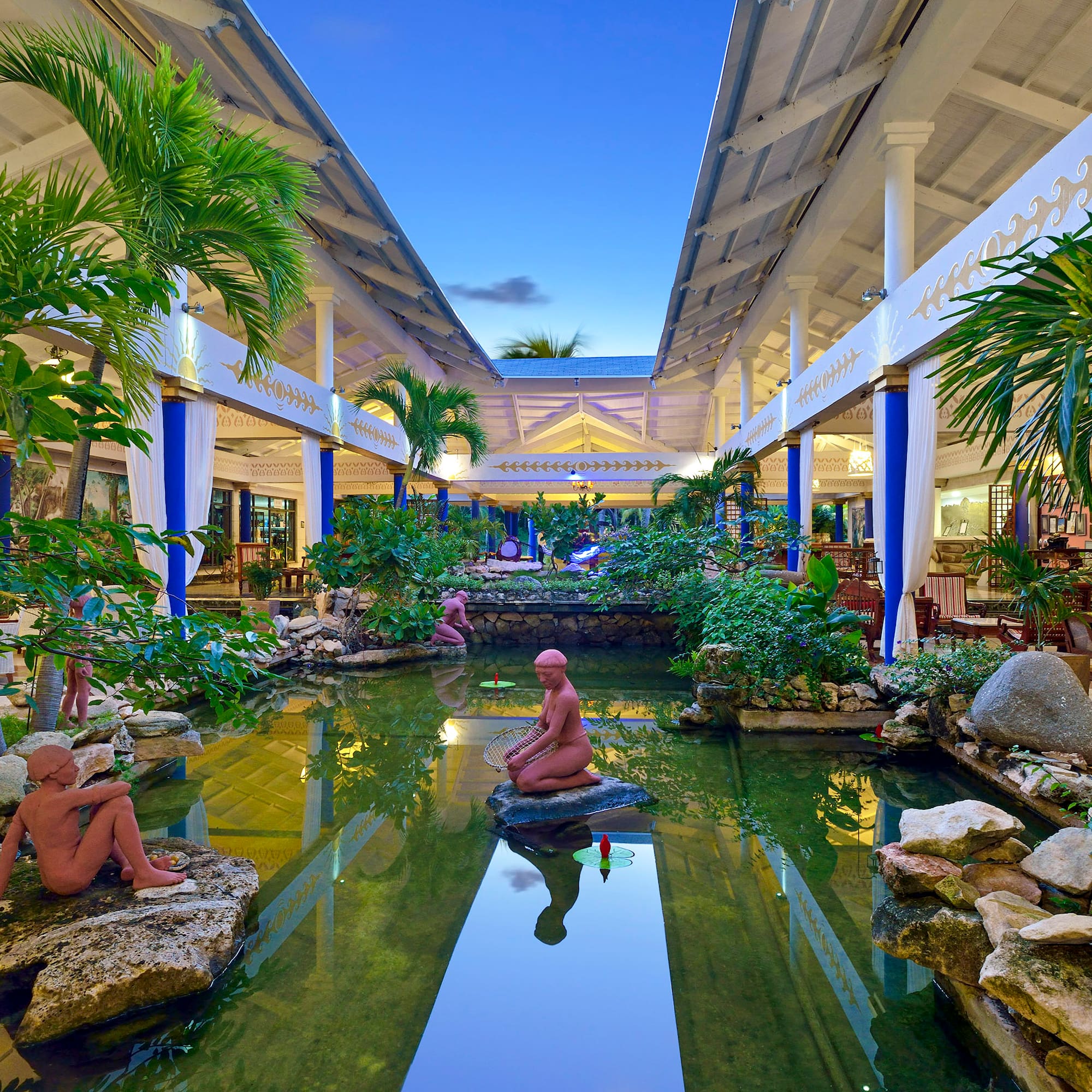 a statue in a pond with trees and plants