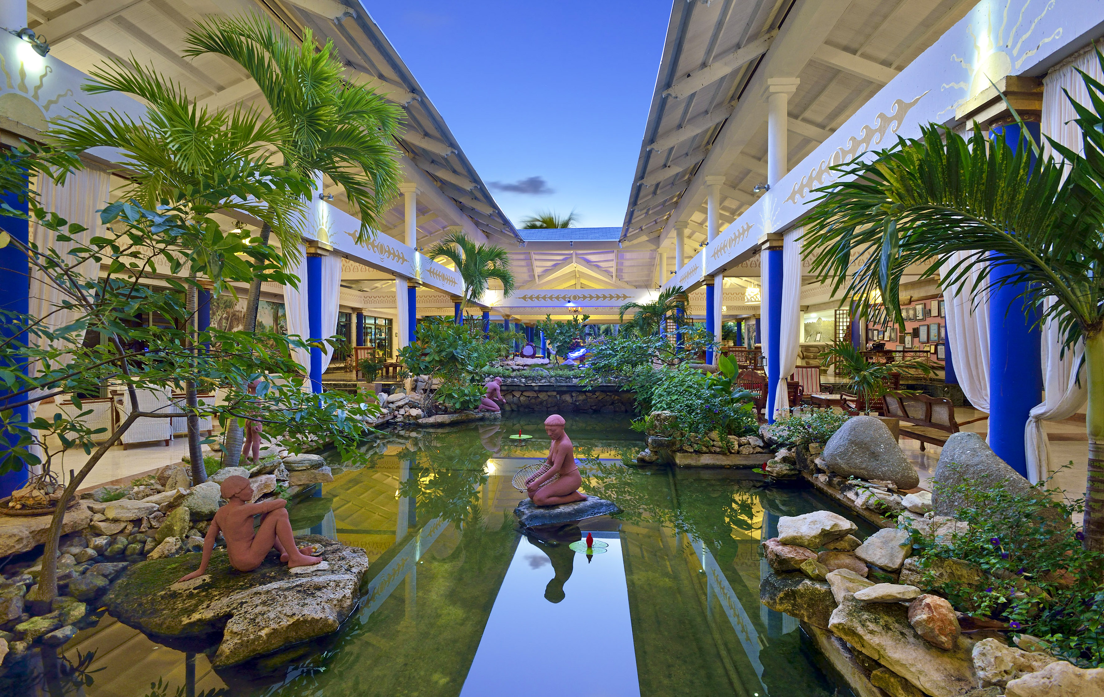 a statue in a pond with trees and plants