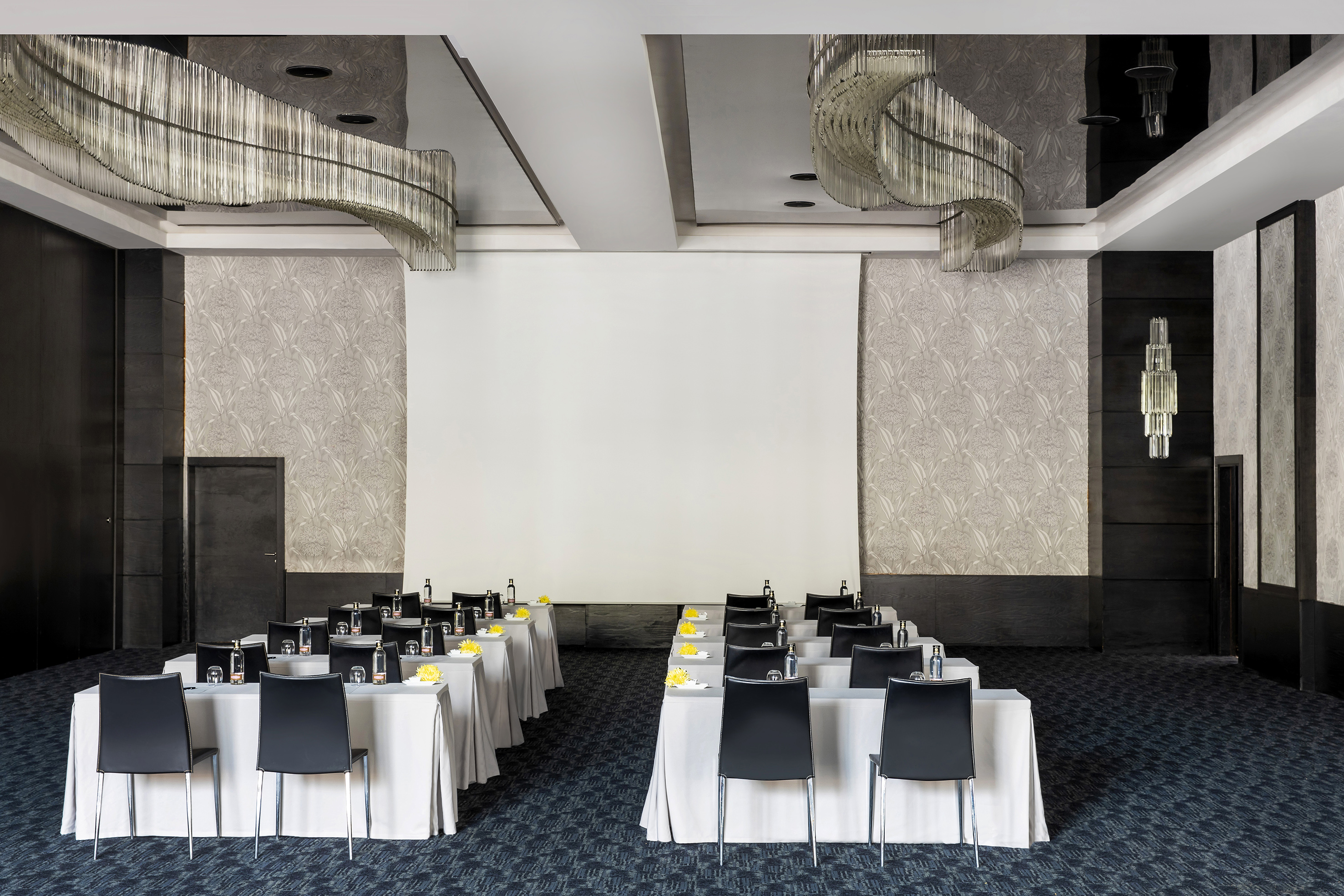 Conference room classroom setup with projection screen and modern chandeliers.