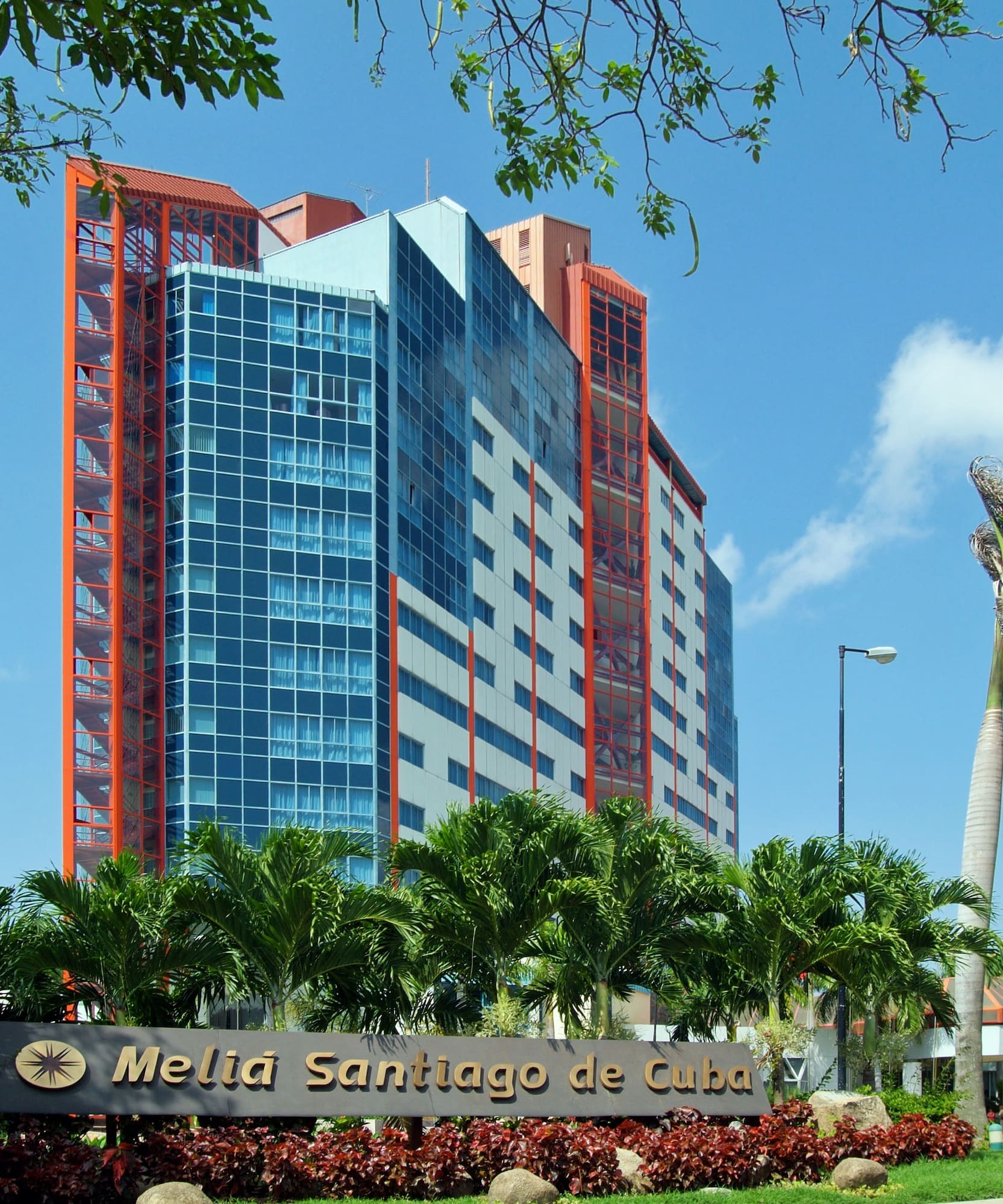 a tall building with palm trees and a sign
