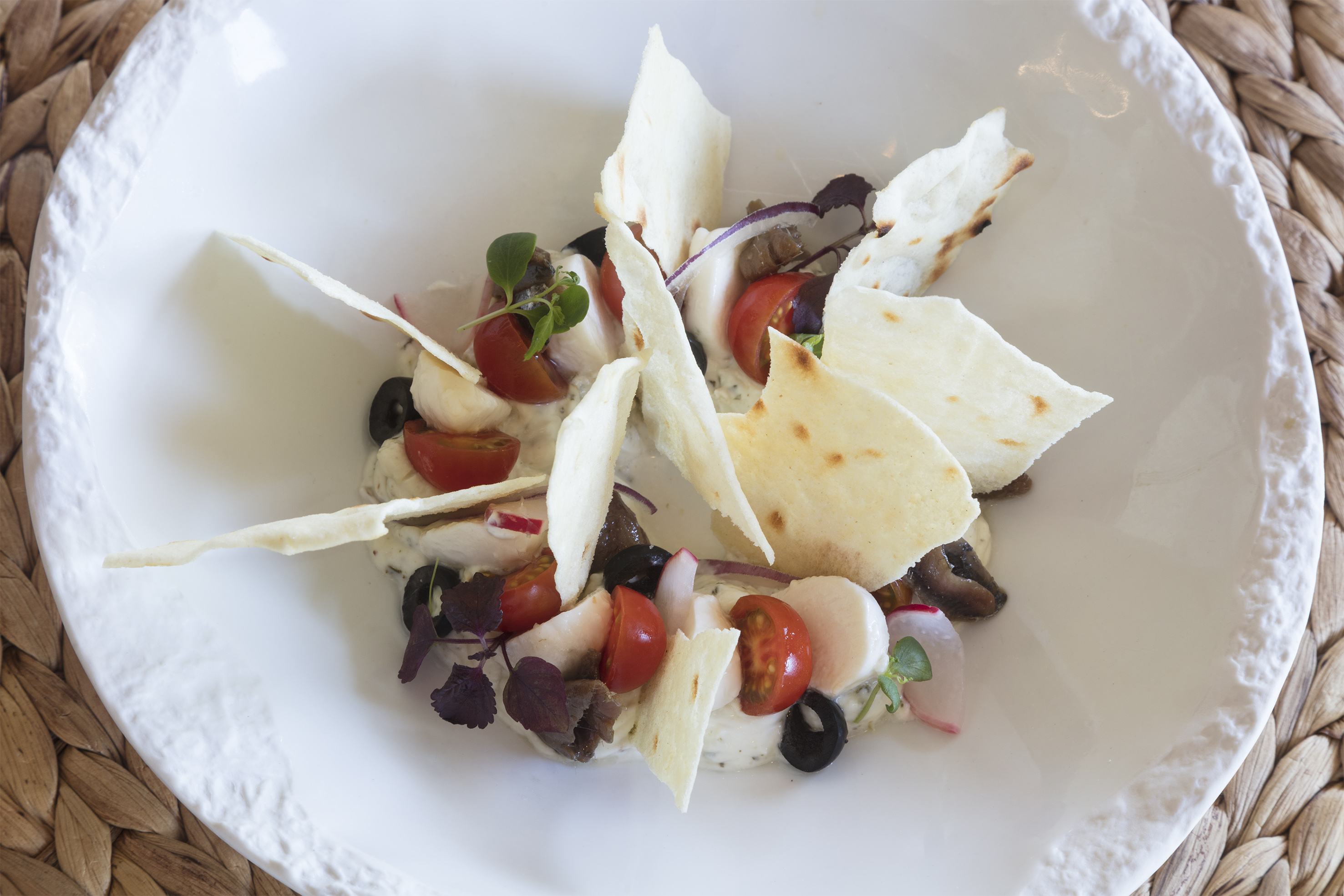Fresh salad with tomatoes, mozzarella, olives, herbs, and toasted flatbread.