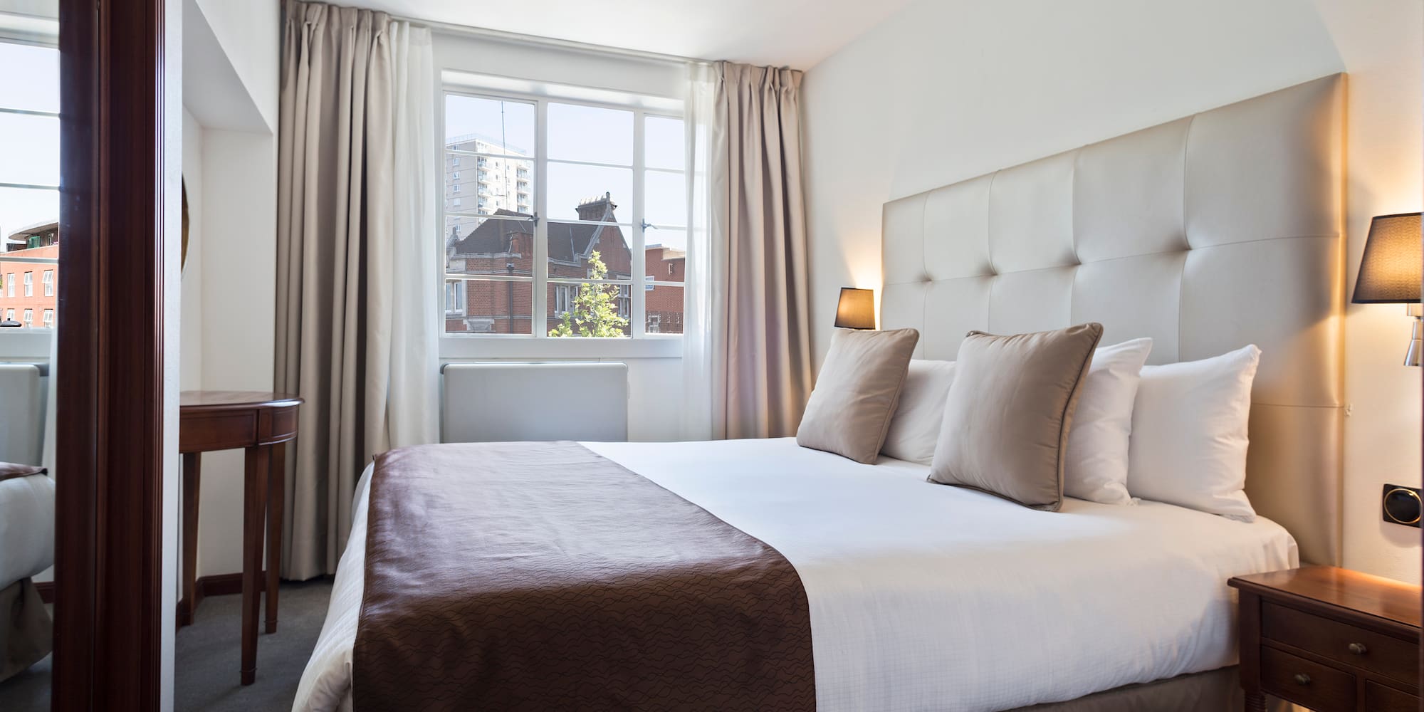 a bed with a brown blanket and a table in front of a window
