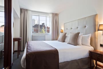 a bed with a brown blanket and a table in front of a window