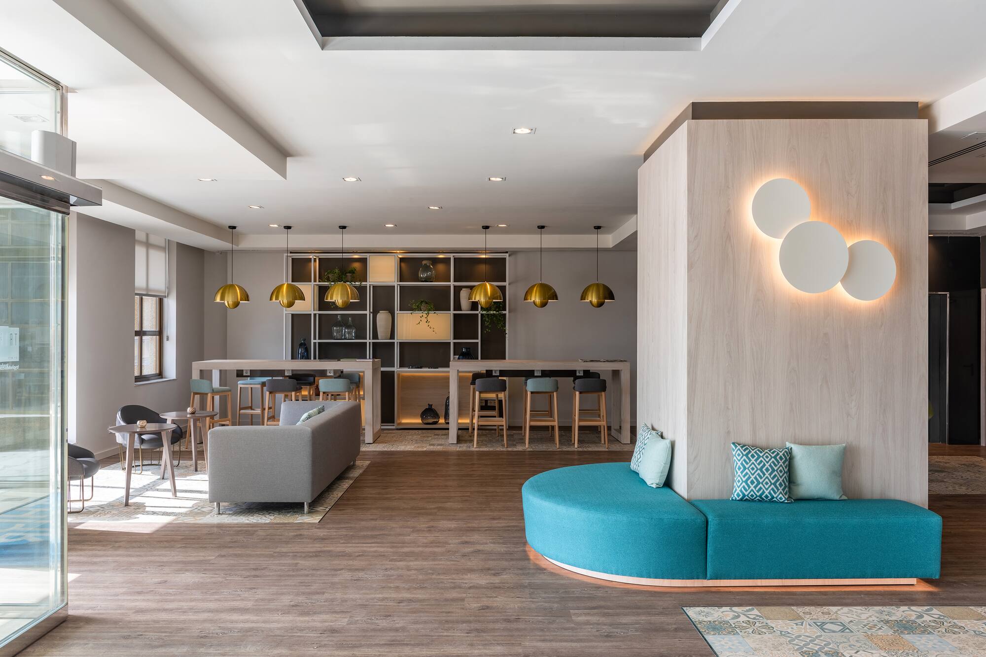 Stylish modern lobby with diverse seating, brass pendants, and circular wall lights.