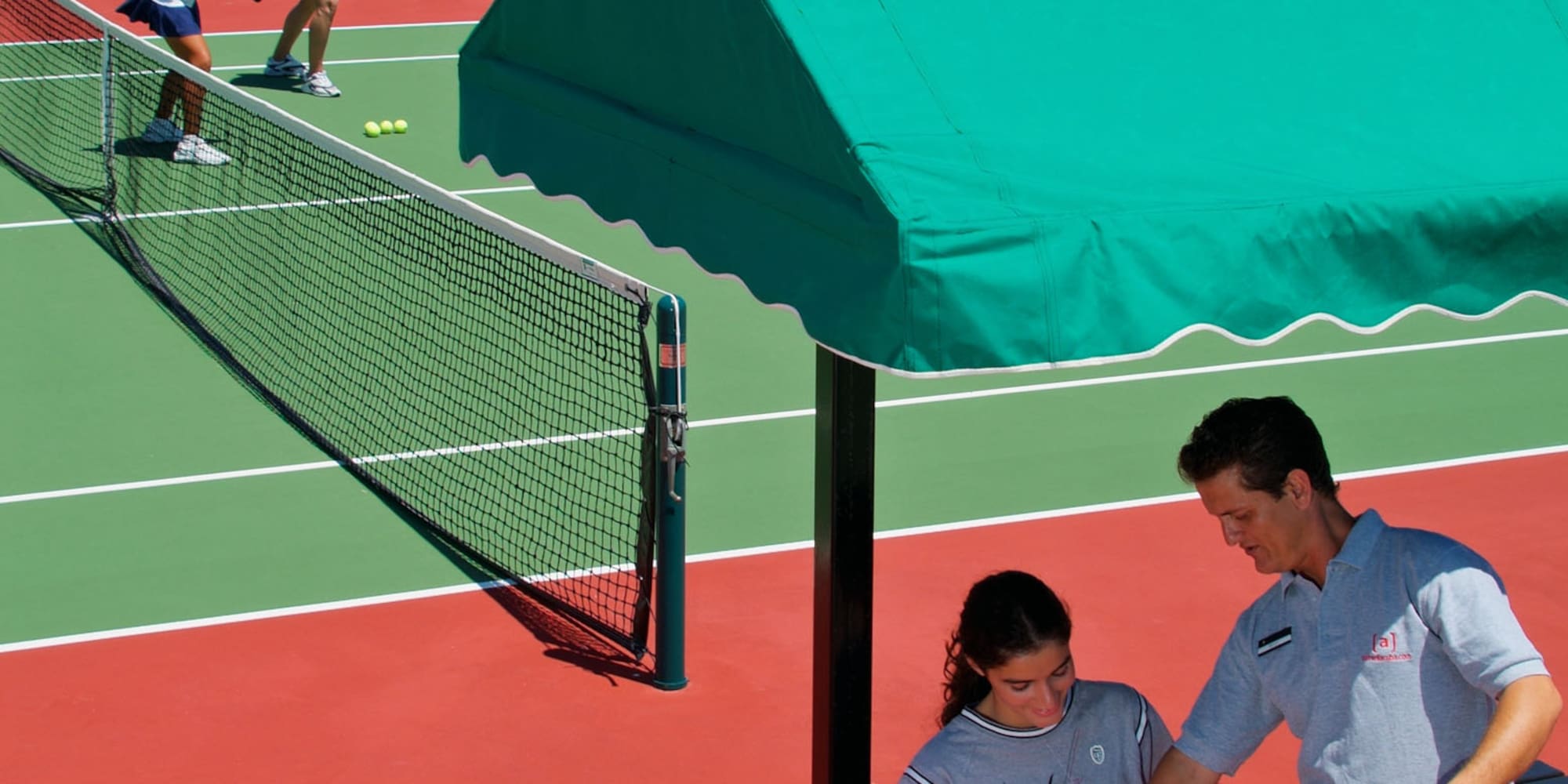 a man and woman sitting on a bench on a tennis court