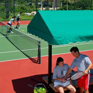 a man and woman sitting on a bench on a tennis court