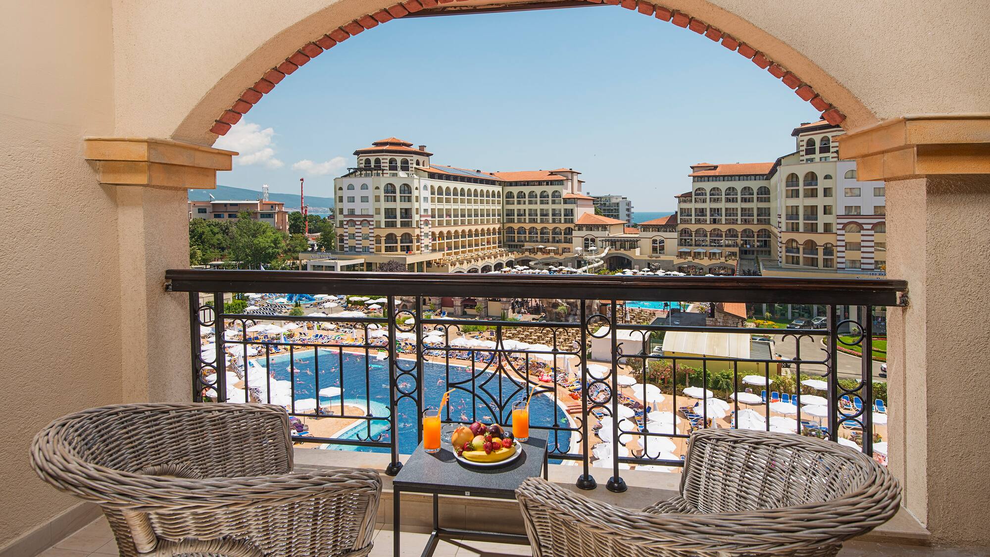 a balcony with chairs and a table with fruit on it