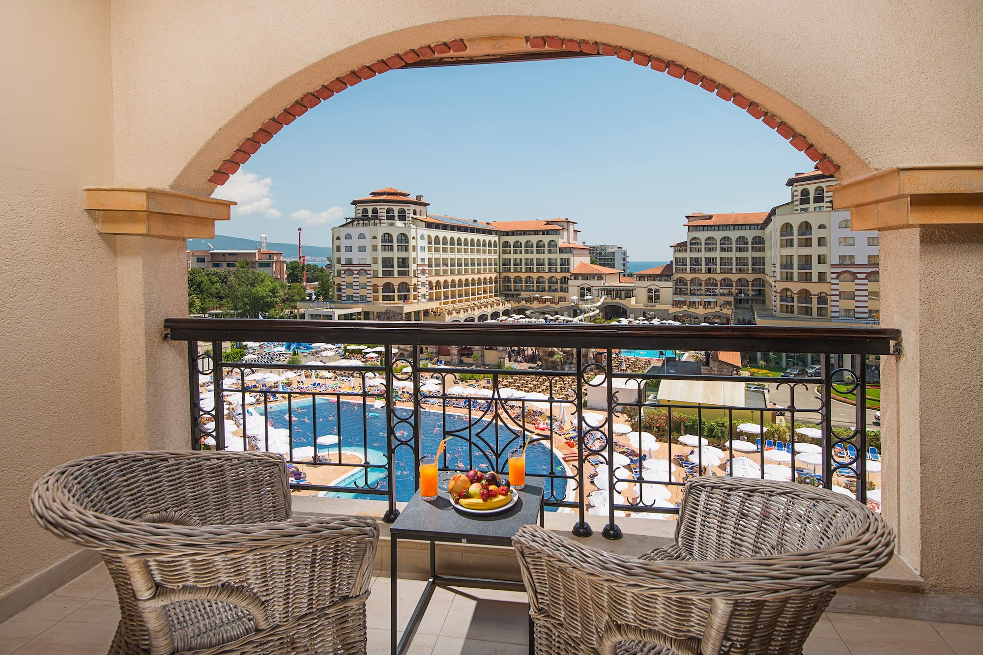 a balcony with chairs and a table with fruit on it