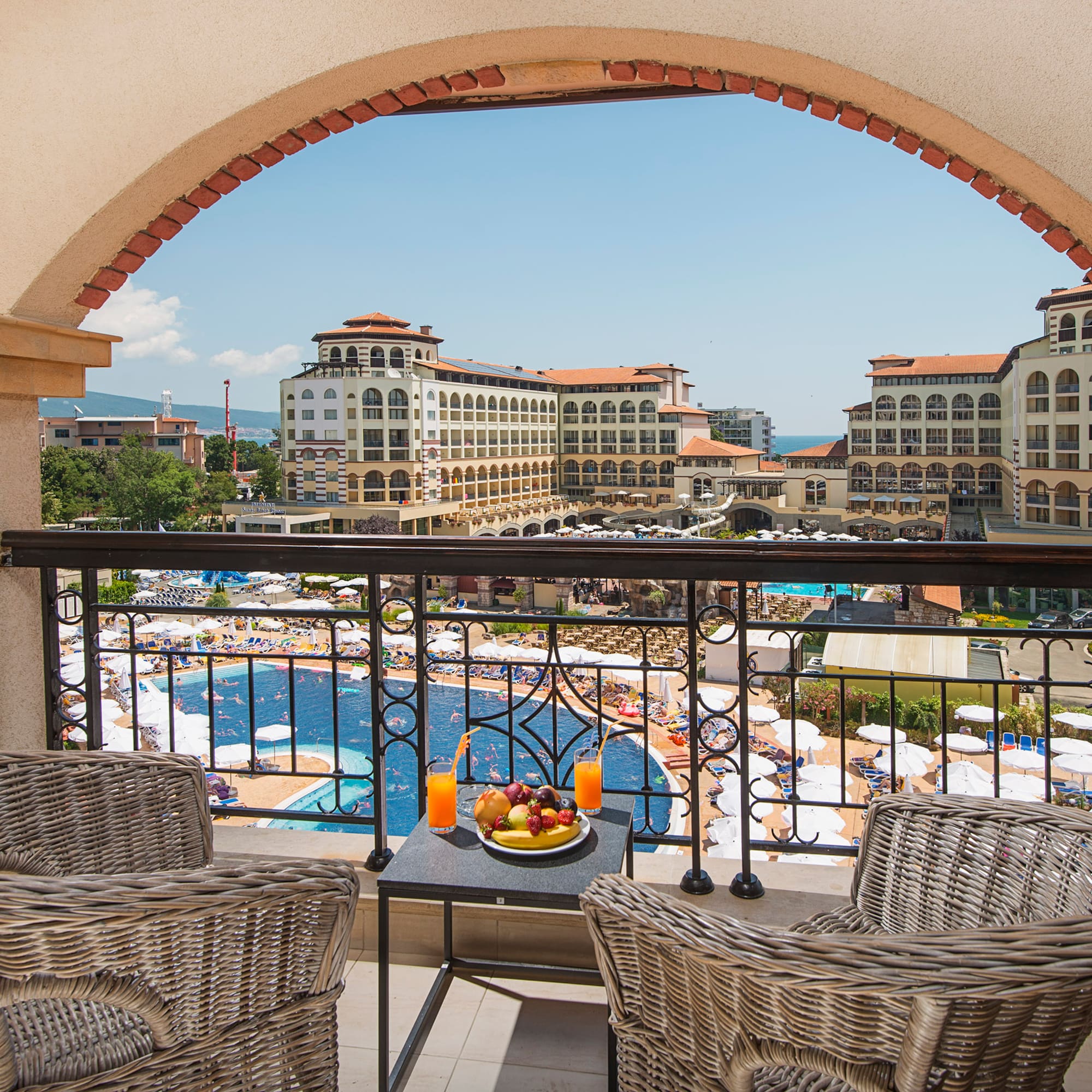 a balcony with chairs and a table with fruit on it