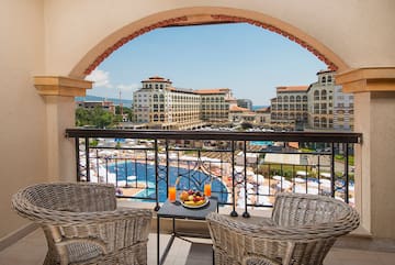a balcony with chairs and a table with fruit on it