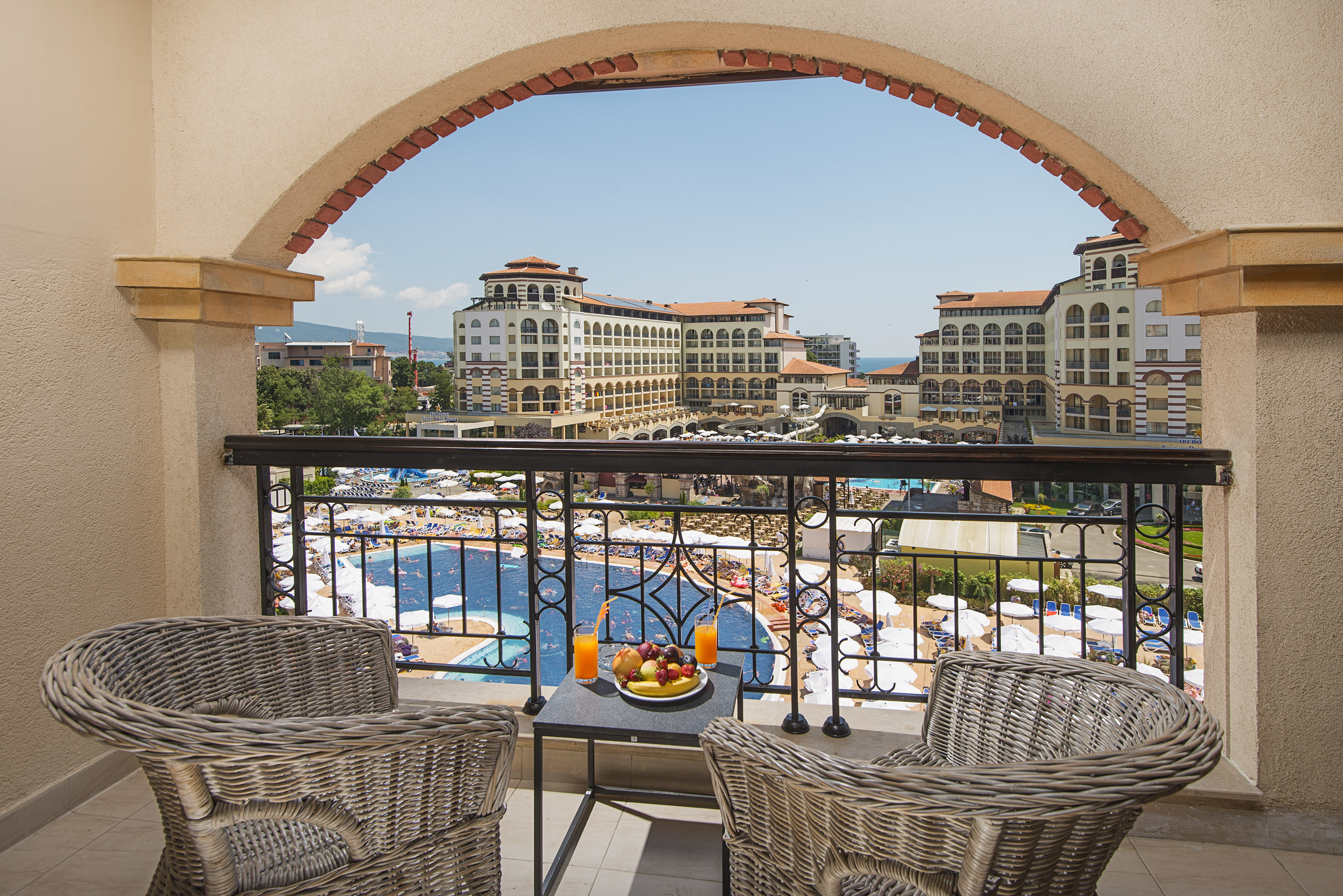 a balcony with chairs and a table with fruit on it