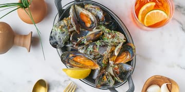 a bowl of mussels with lemon and a glass of liquid