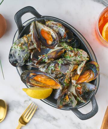 a bowl of mussels with lemon and a glass of liquid