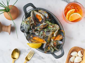 a bowl of mussels with lemon and a glass of liquid
