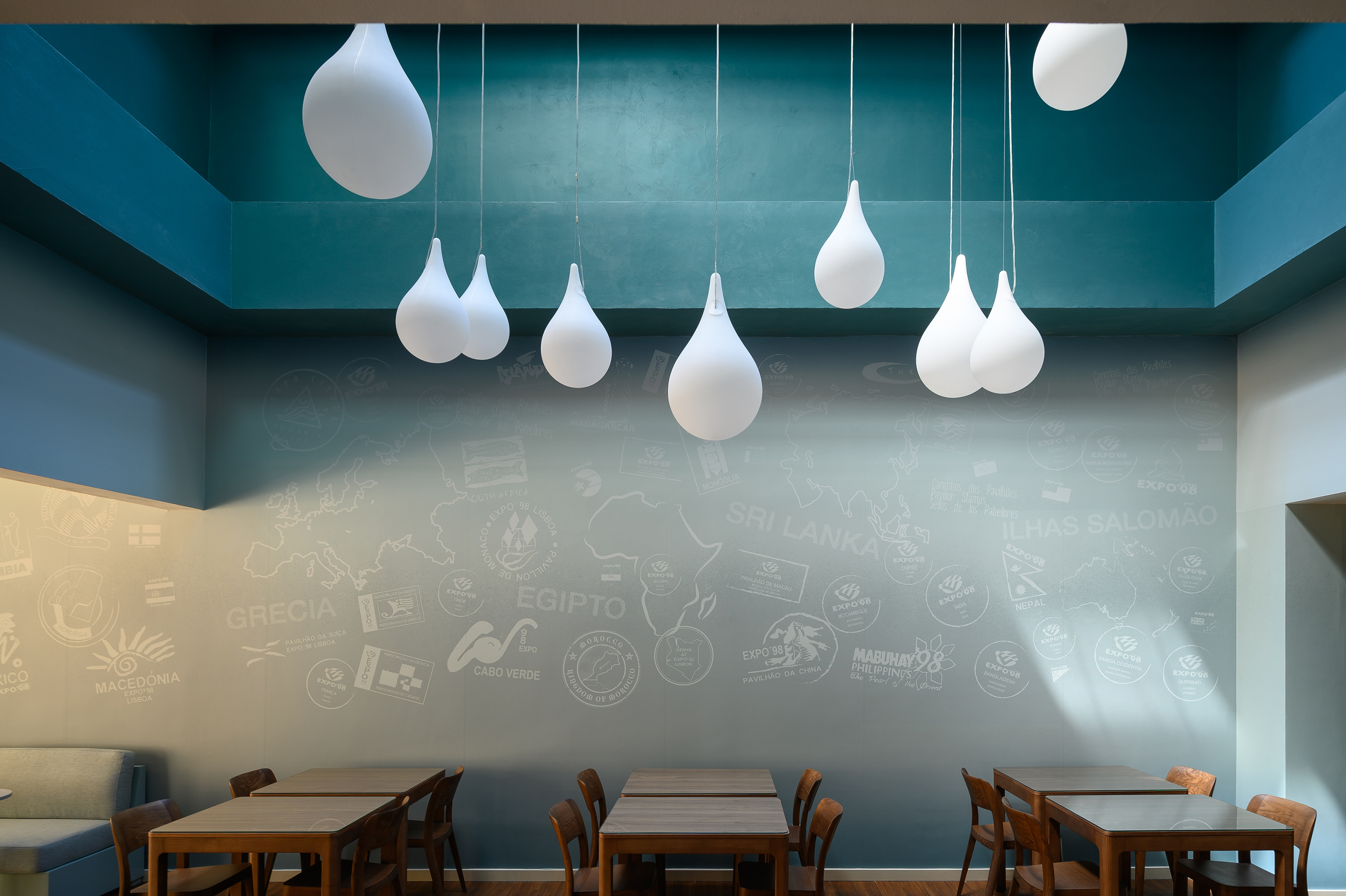 Teal dining room with Expo '98 world map mural, white pendant lights.