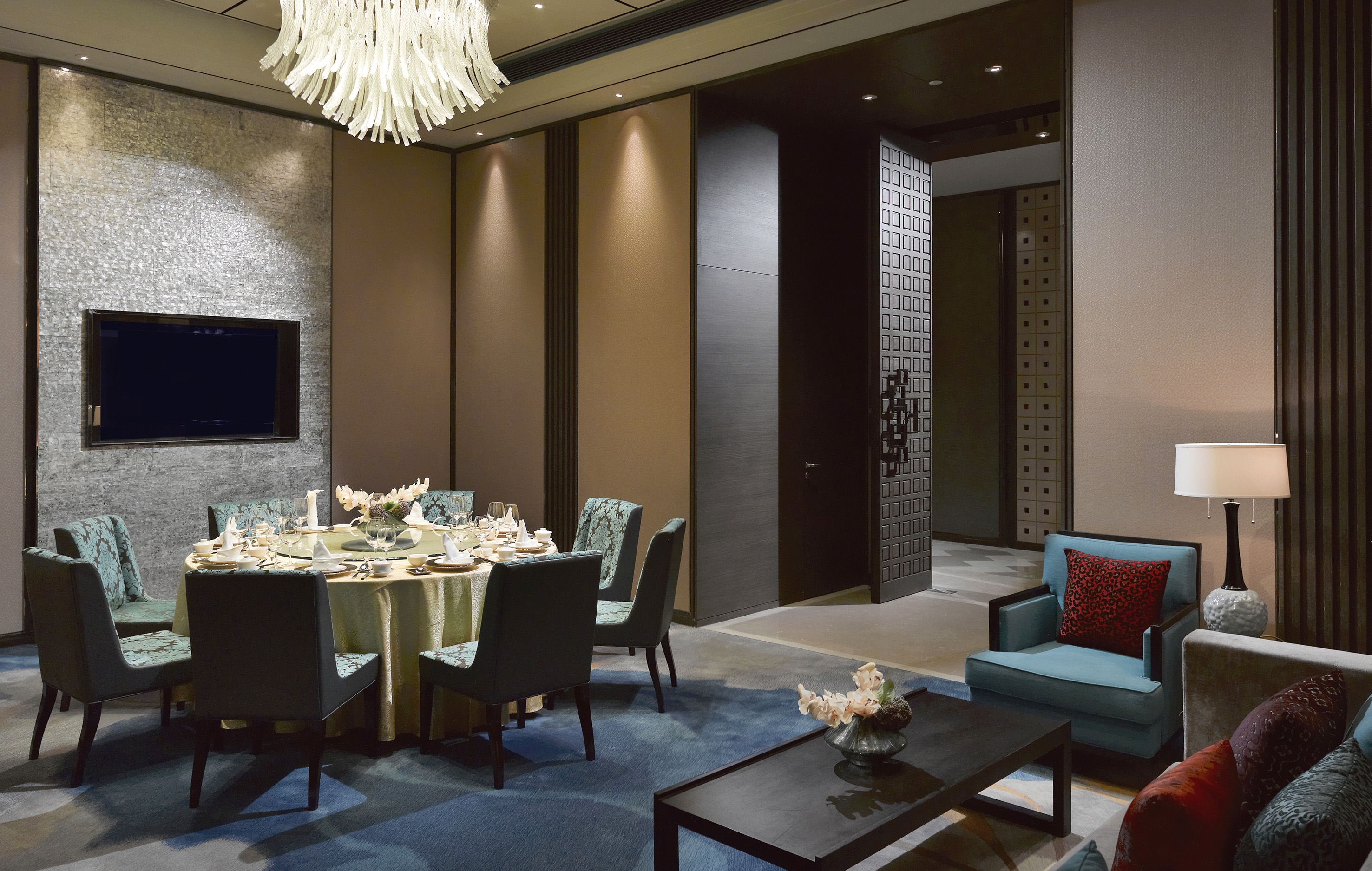 Elegant private dining room with round table, modern chandelier, and lounge seating.