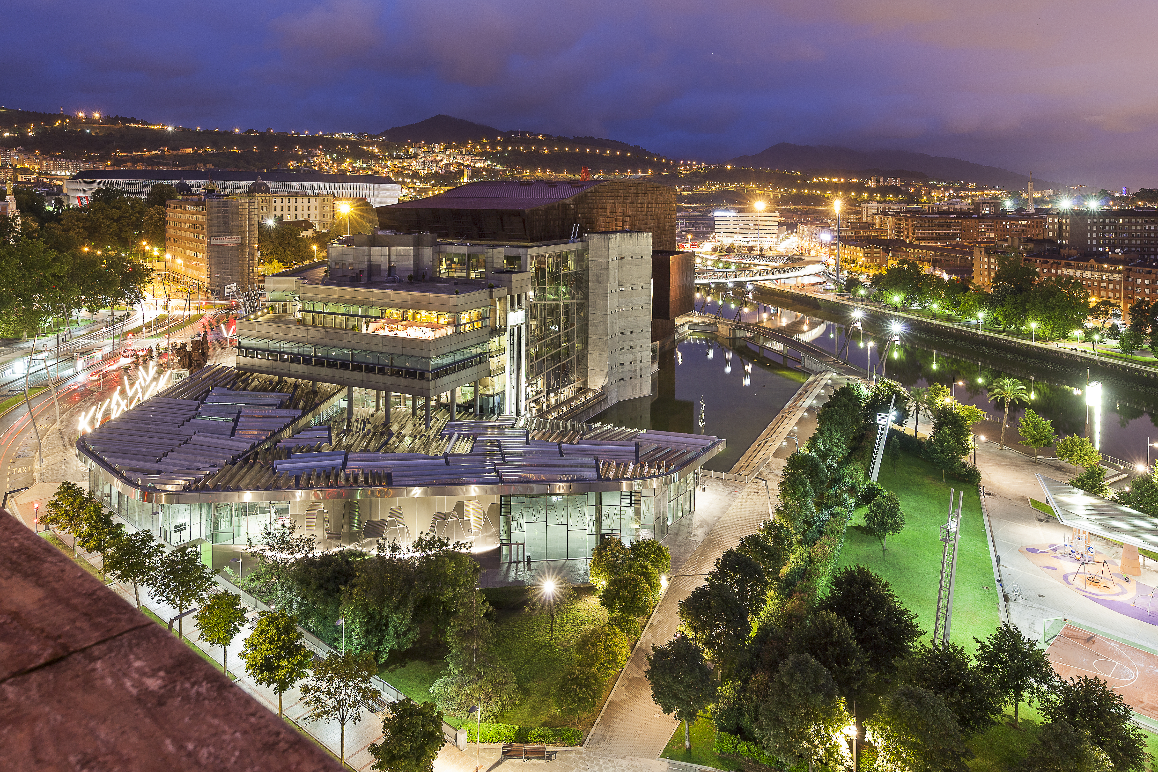 Bilbao Euskalduna Centre at night, modern architecture, river, city lights.