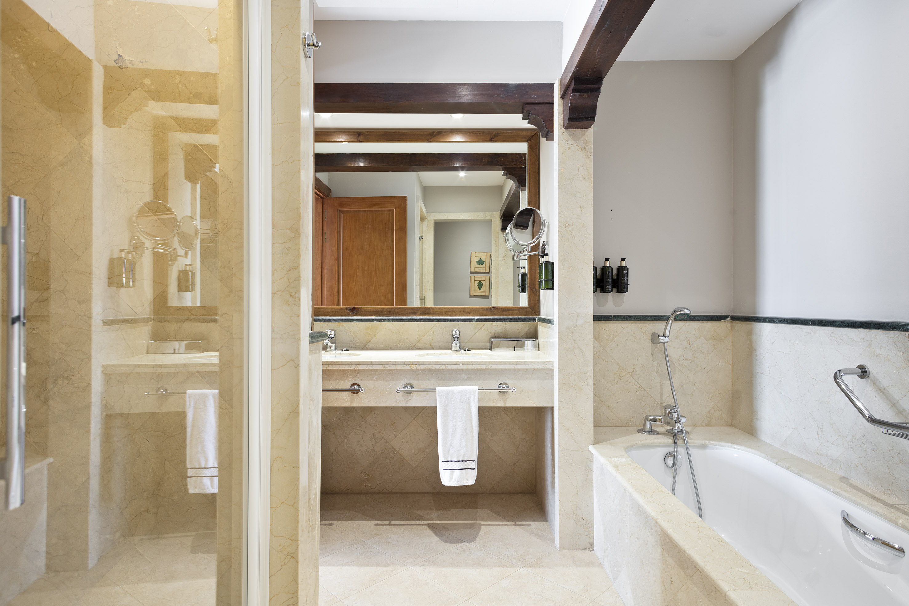 Luxurious marble hotel bathroom with double vanity, shower, and bathtub.