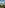 Mediterranean village resort with golf course and mountains under blue sky.