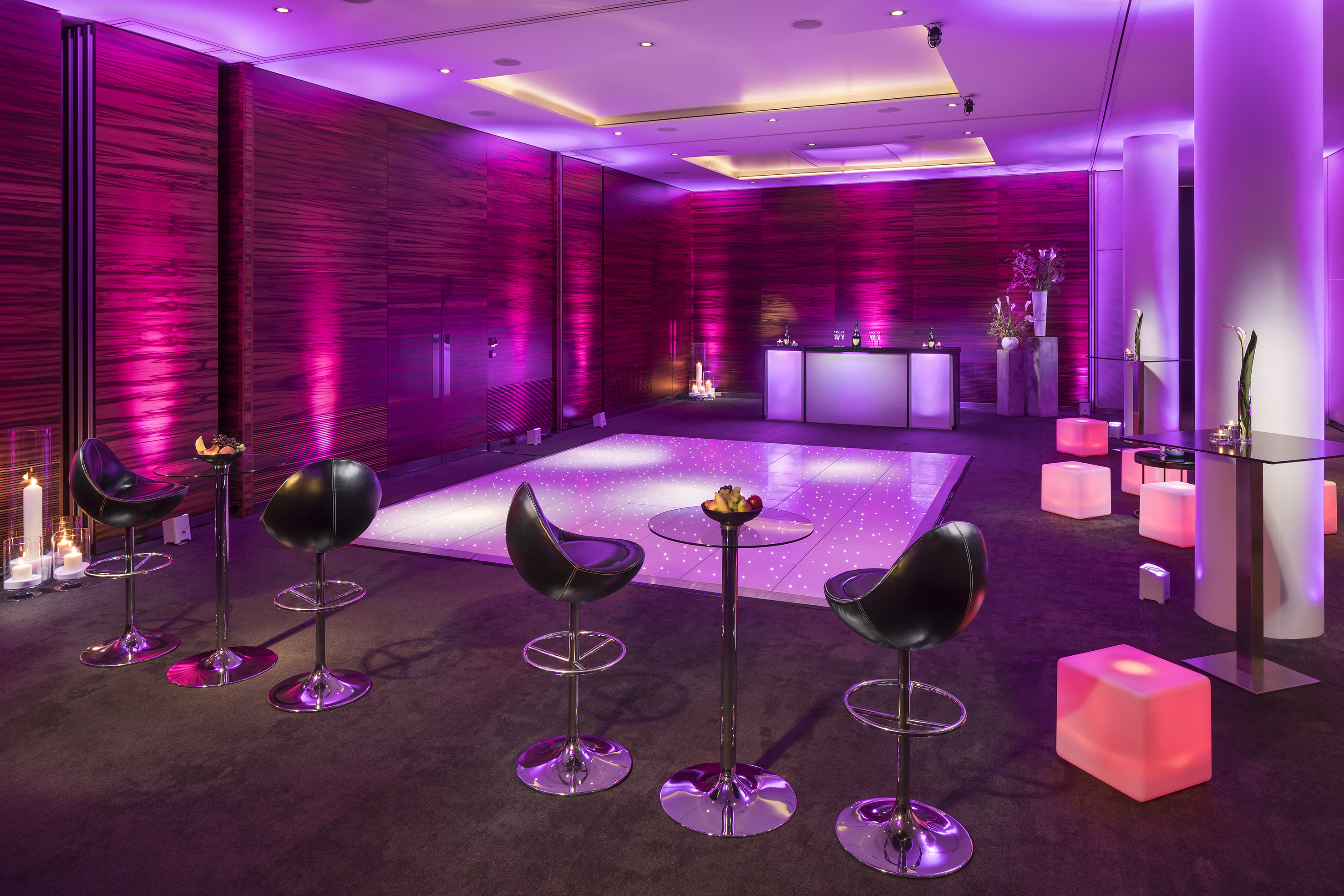 Magenta lit event lounge with starry dance floor, bar, and cocktail seating.