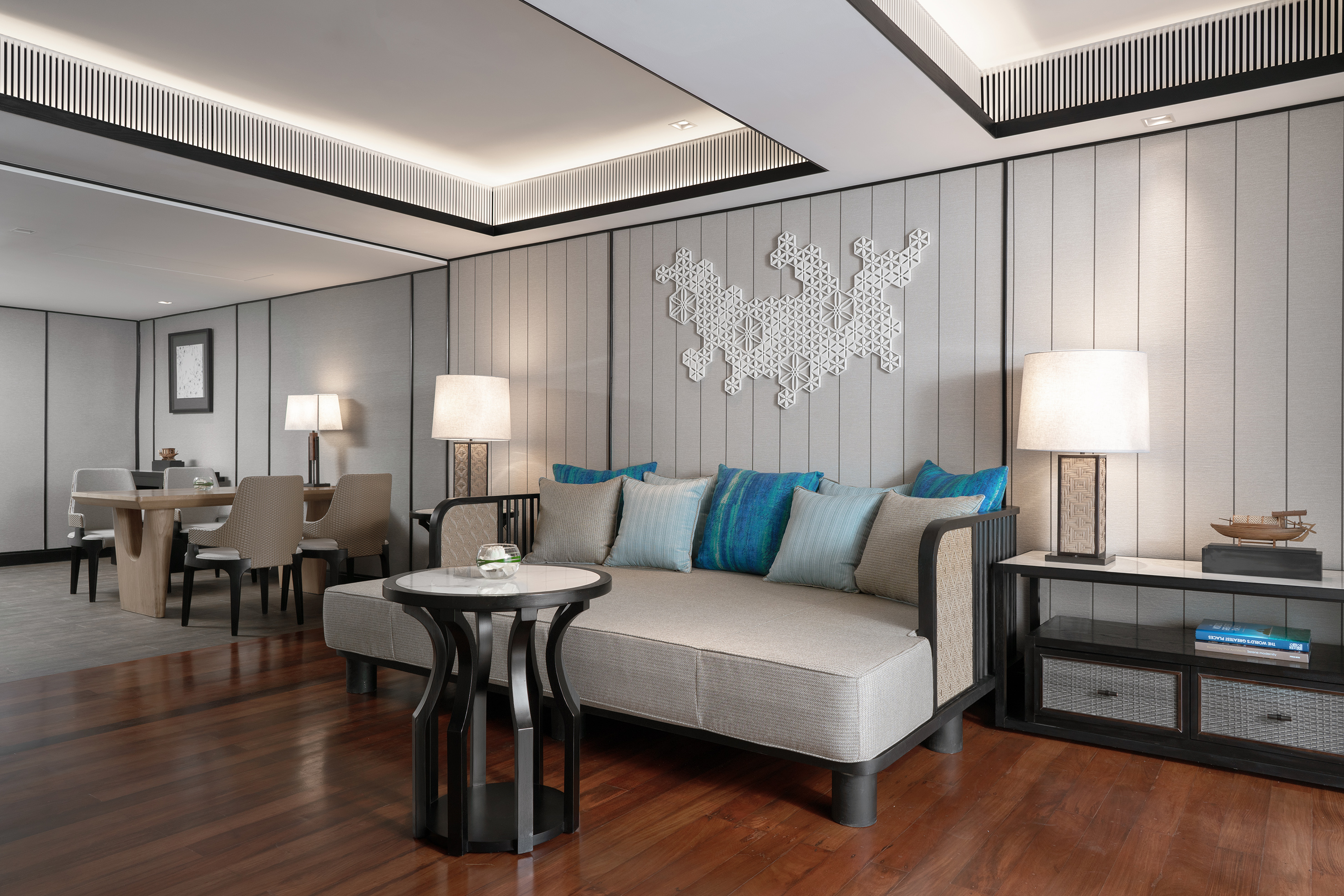 Modern living room with daybed, blue pillows, wooden floor, and geometric wall art.