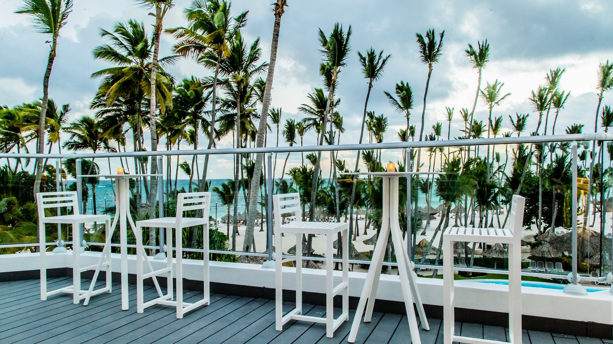 a white table and chairs on a deck overlooking a beach