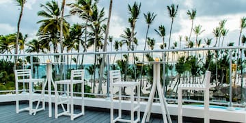 a white table and chairs on a deck overlooking a beach