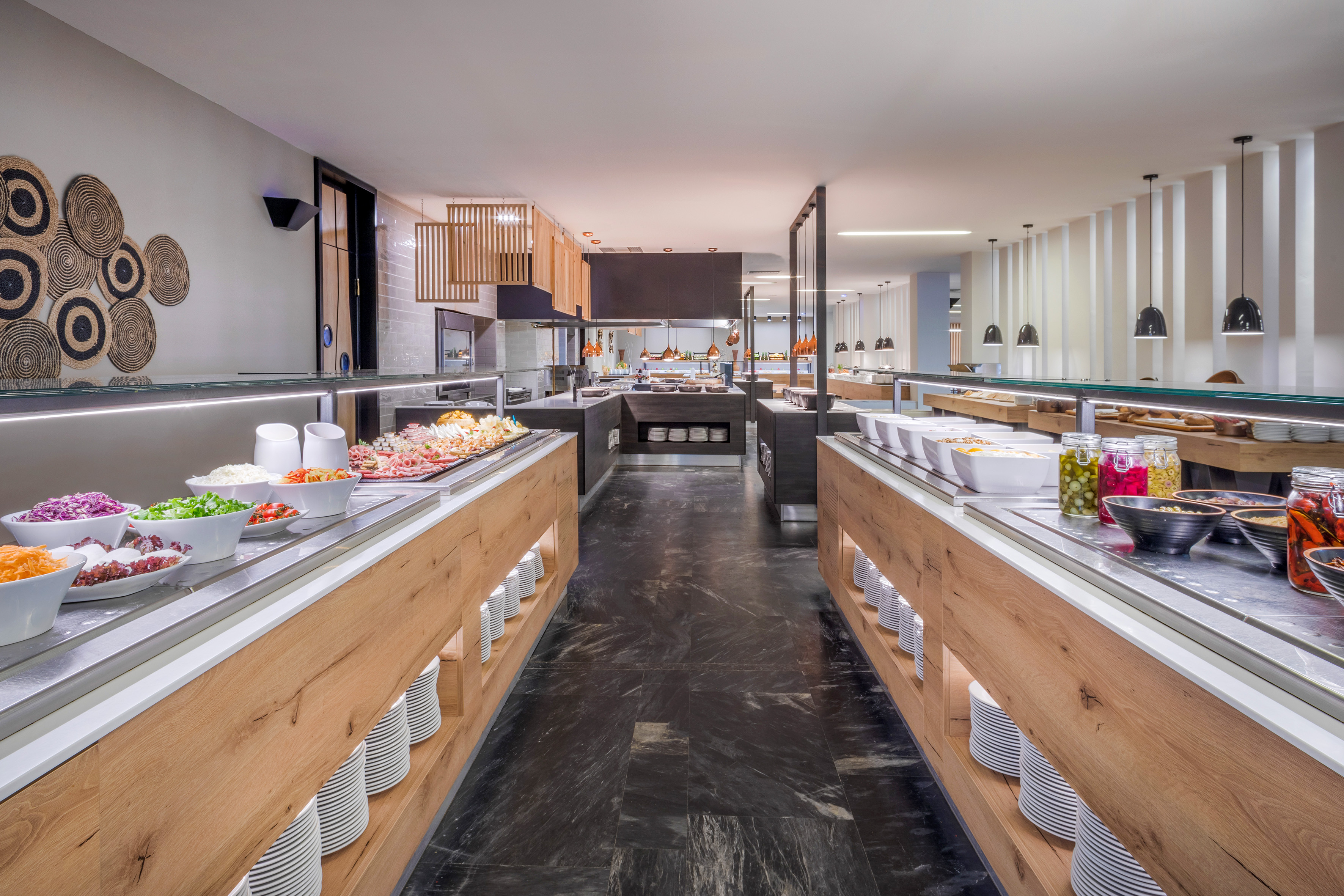 Spacious modern hotel buffet with fresh salads, cold cuts, and dining counters.