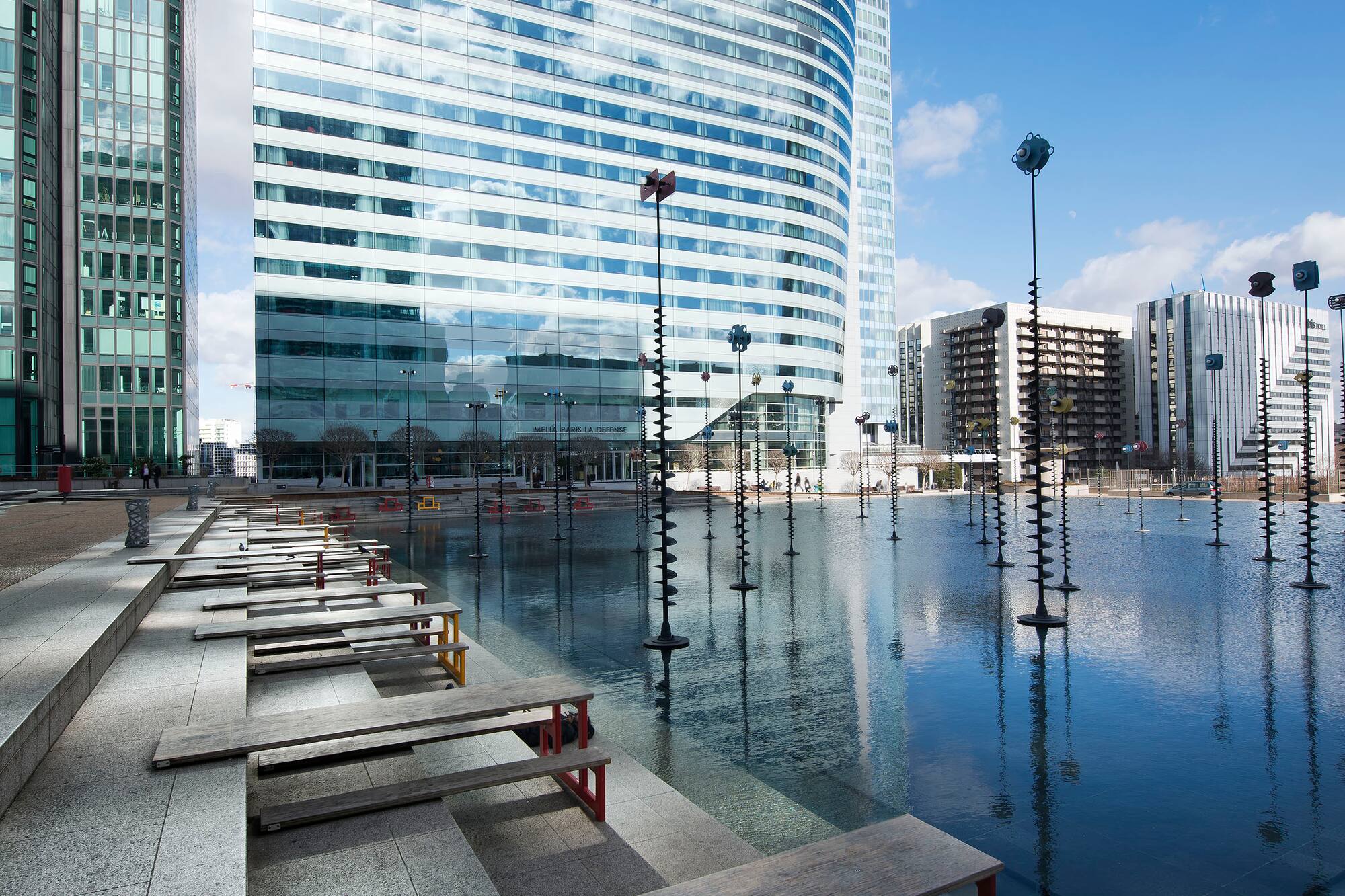 La Defense urban plaza with modern glass towers, water features, and unique sculptures.