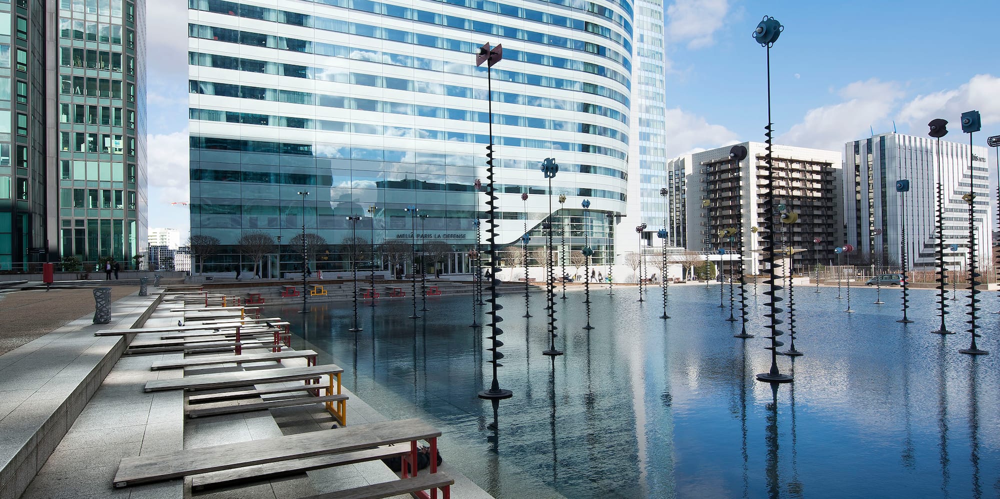 a water with benches and a large building in the background